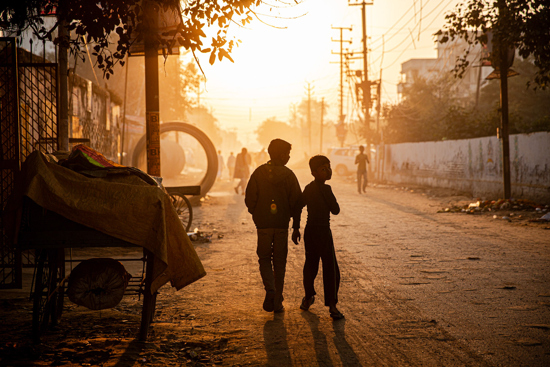 Kids walking at sunrise in a dirt road. Varanasi, India