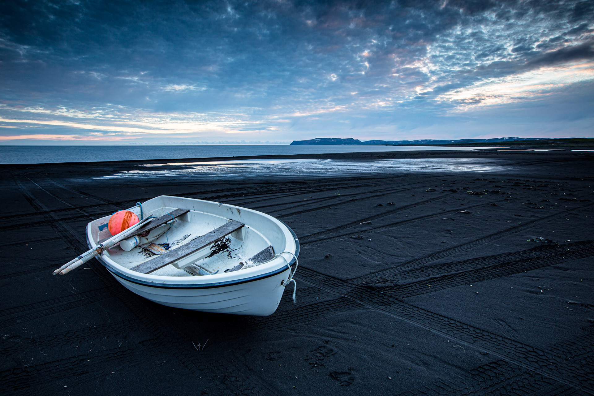 White boat in black sand beach. Iceland
