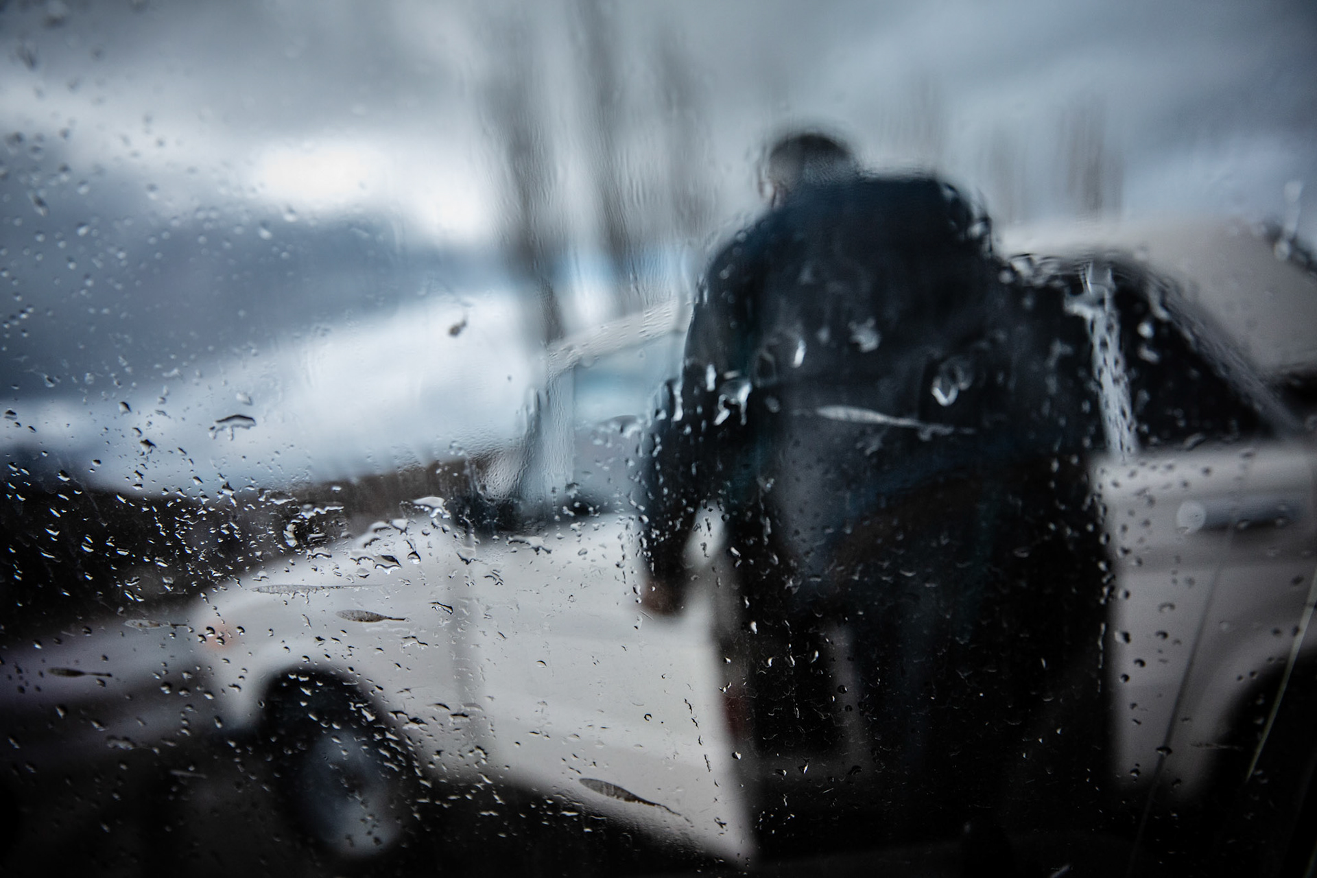 A man at Zovasar entering his Lada car in the rain. Armenia