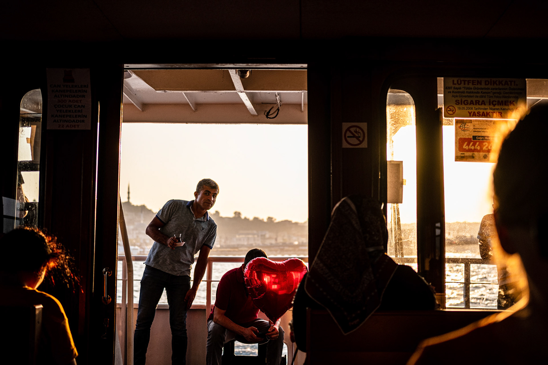 Istanbul, Turkey - 25 August 2019 : Man holding an heart shaped balloon inside an Istanbul ferry