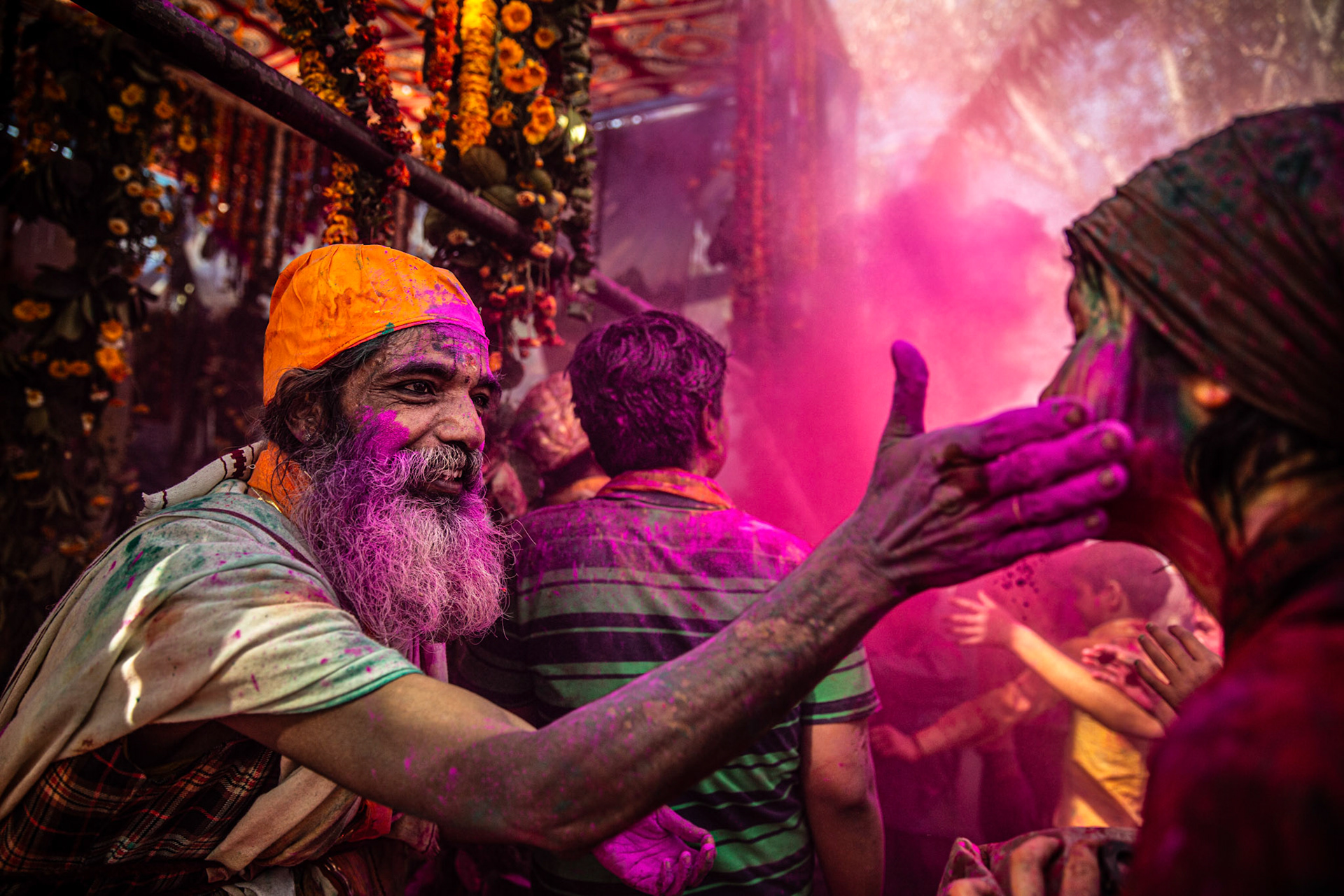 Man putting pink gulal in a foreigner girl's face during Holi. Mathura, India