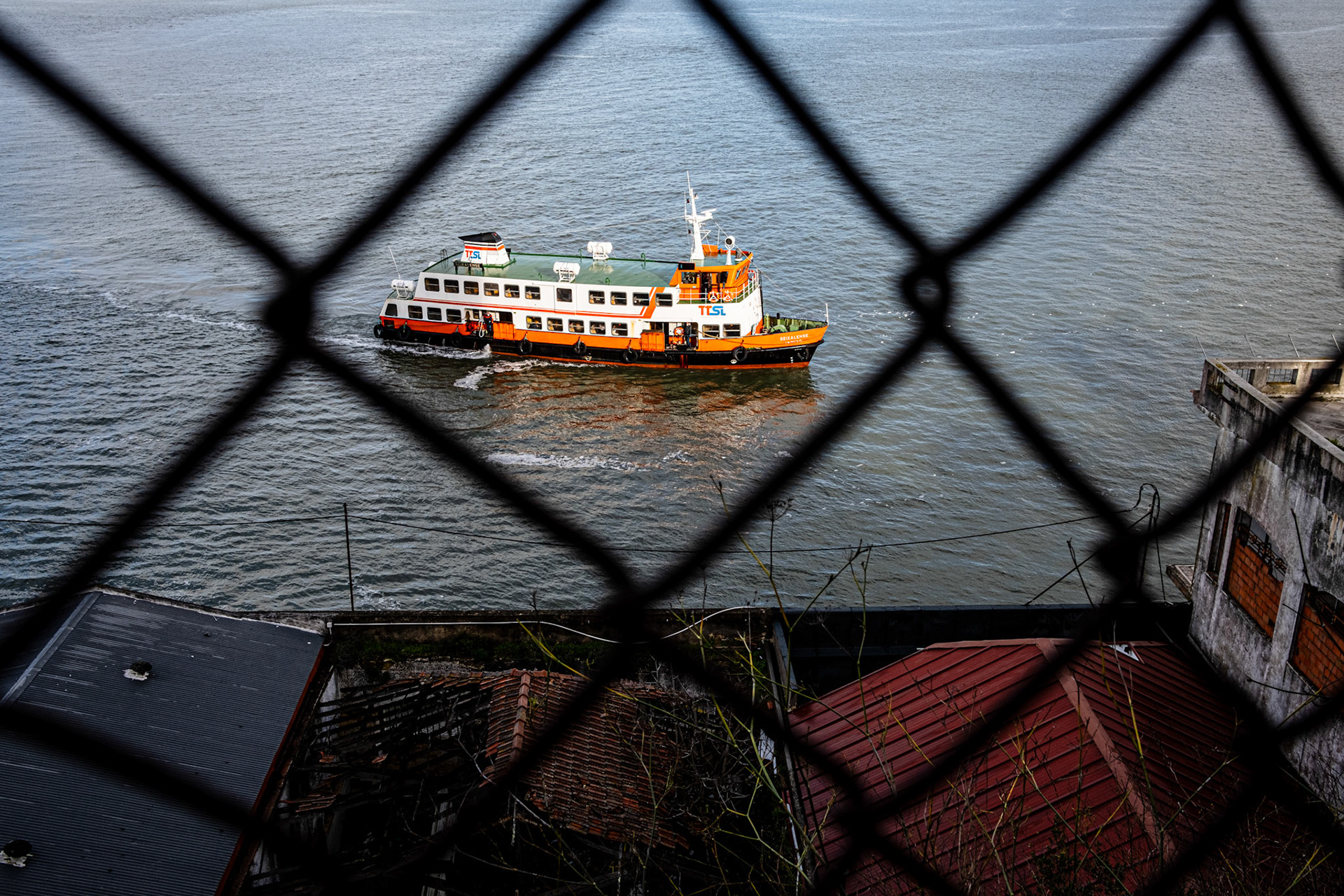 Almada, Portugal - 31 December 2020 : Cacilheiro seen through a fence