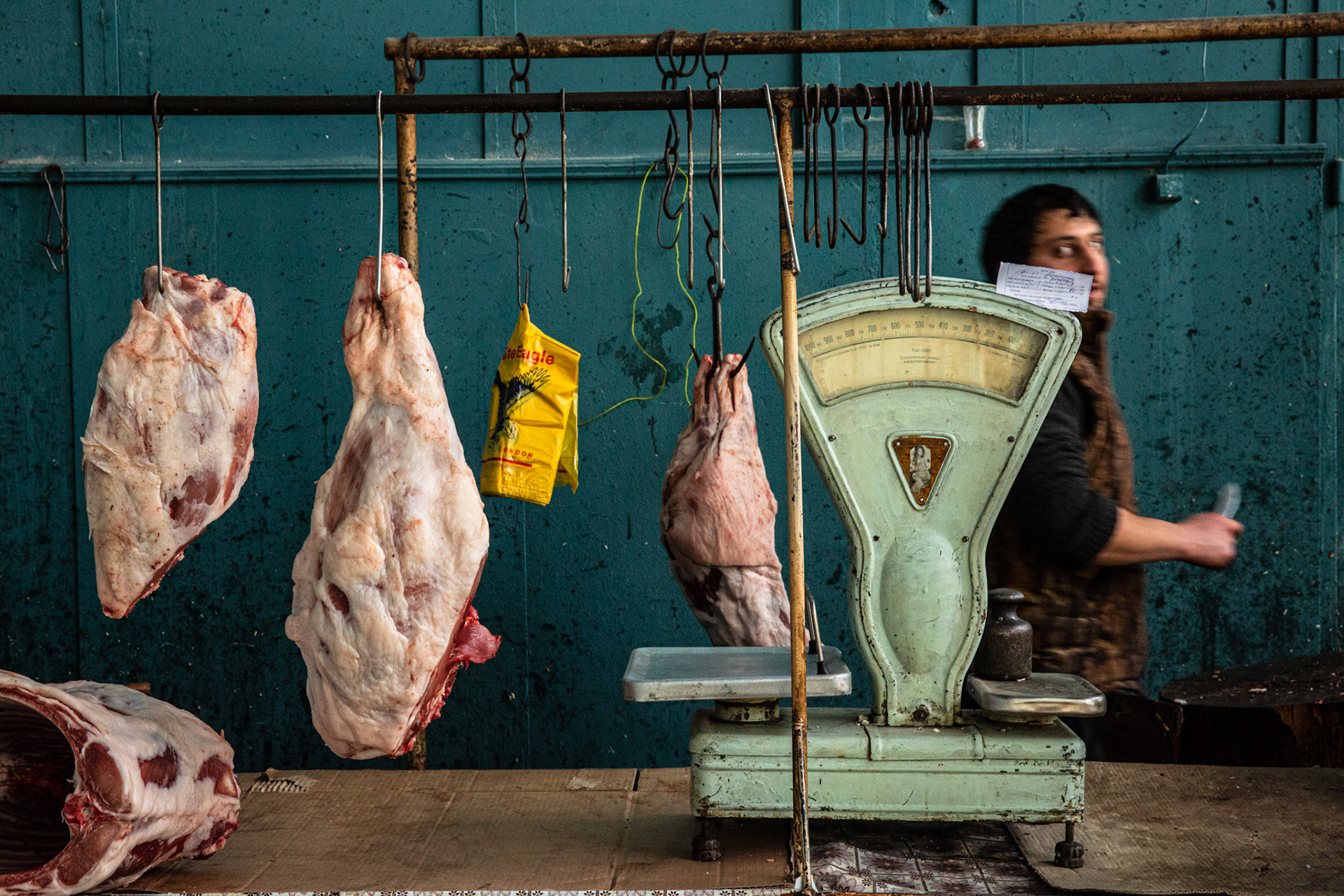 Butcher passing by pieces of meat at Gyumri's market. Armenia