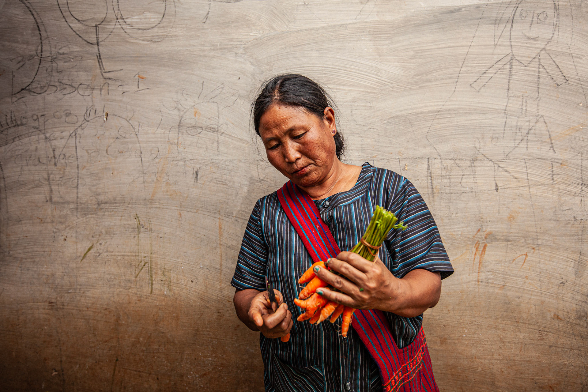 Woman preparing a bunch of carrots at Nyaung Shwe Market. Myanmar