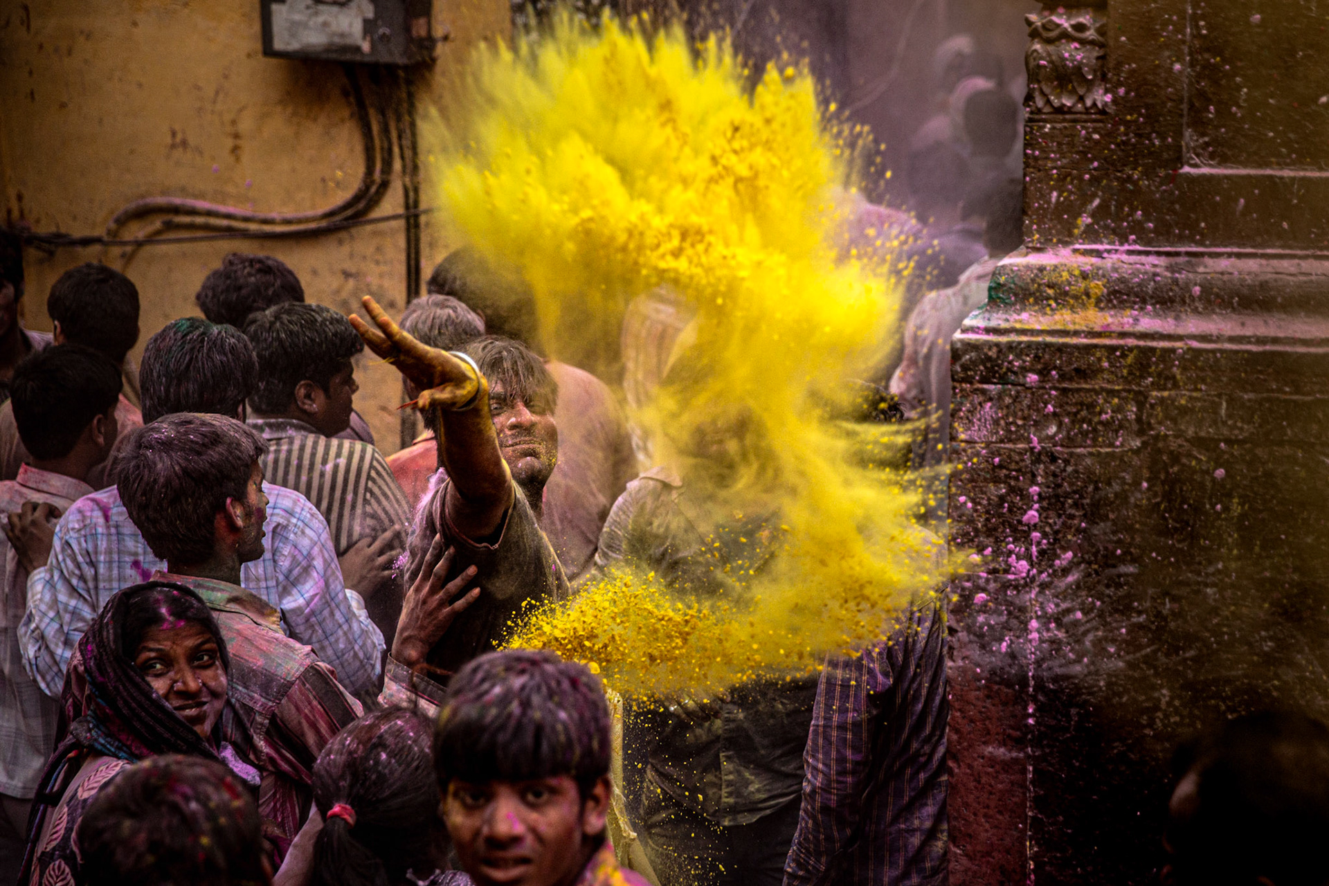Man throwing yellow gulal outside Bankey Bihari temple. Vrindavan, India