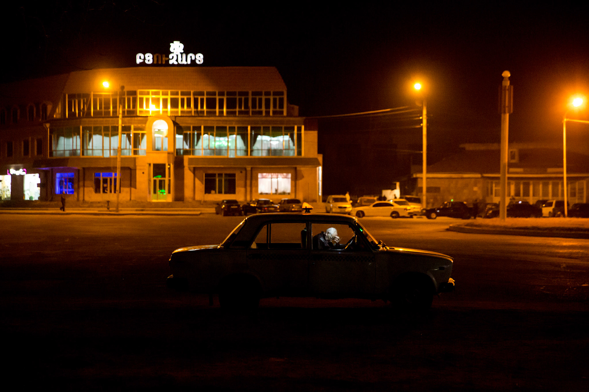 Taxi driver checks on his mobile phone while parked in a square. Gyumri, Armenia