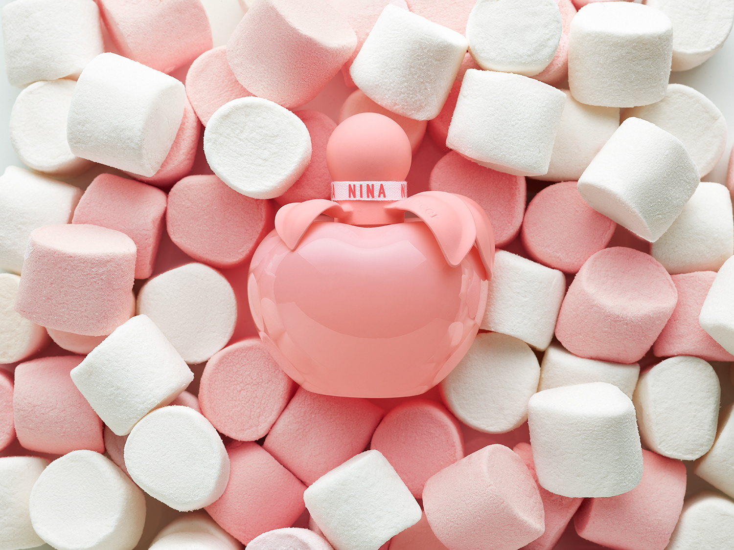 Nina Ricci Parfums : Nina Rose, photographie de nature morte, parfum, photographie de flacon de parfum Nina Rose sur un lit de chamallows gourmands rose et blanc - PALAST PHOTOGRAPHIE, Paris France