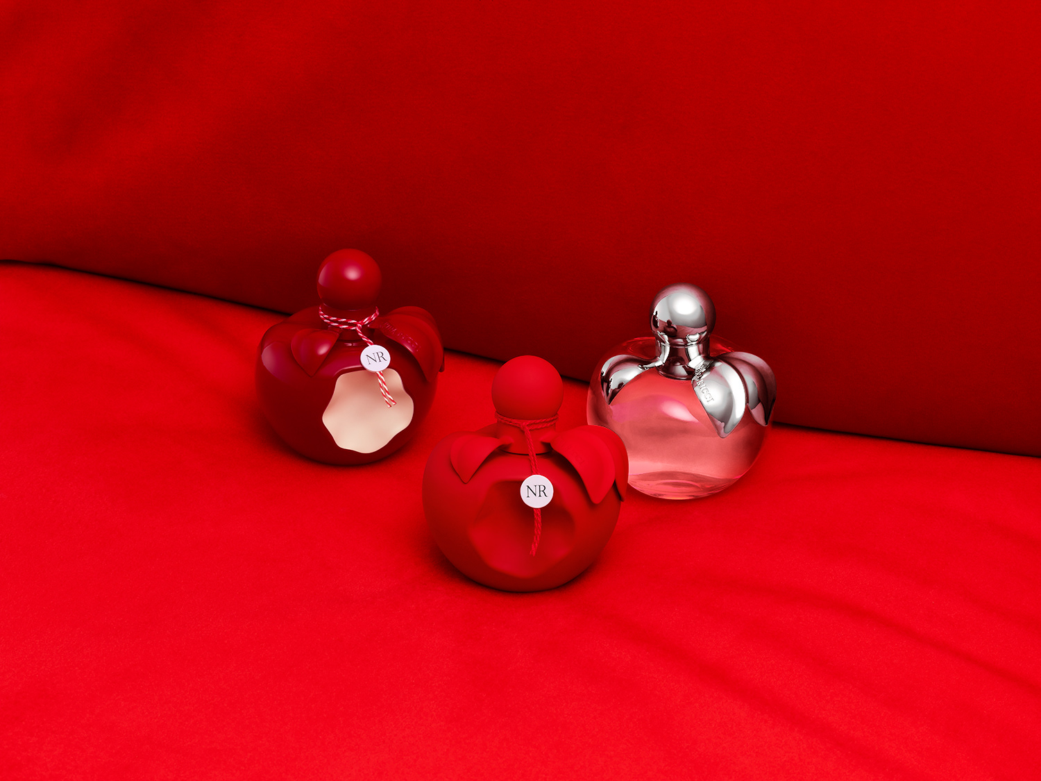 Nina Ricci Parfums : Nina extra rouge, photographie de nature morte, parfum, photographie de flacons Nina Ricci sur une banquette en velours rouge - PALAST PHOTOGRAPHIE, Paris France