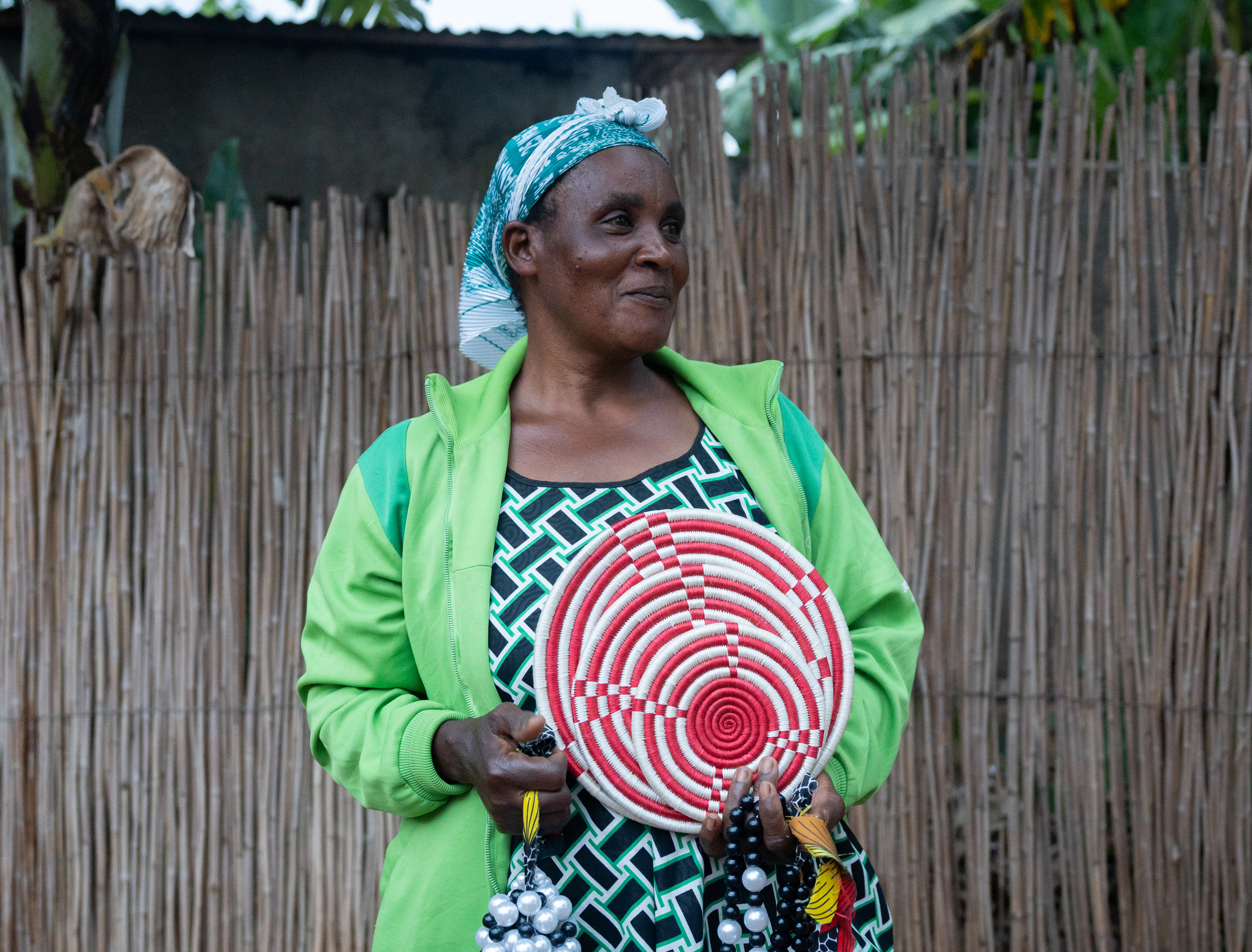Anna Maria poses with woven pieces she made on Wednesday, May 20, 2026 in Unity Mountain, Rwanda.  Anna Maria is part of a cooperative formed by women who are survivors and wives of perpetrators of the genocide. Their larger community is Umusozi w'Ubumwe, Unity Mountain, a reconciliation community led by Rabagirana Reconciliation Hub.   Rabagirana is a Rwandan, Christian organization that focuses on reconciliation and peace-building after the genocide. It involves faith as a piece of common ground for community members to come together through.   Among the items made by the women are peace baskets, which have become the national symbol of Rwanda as markers of the progress in unity, hope, and reconciliation the country has made over the past three decades. (Evan Frilingos/ Evan Frilingos 2026)