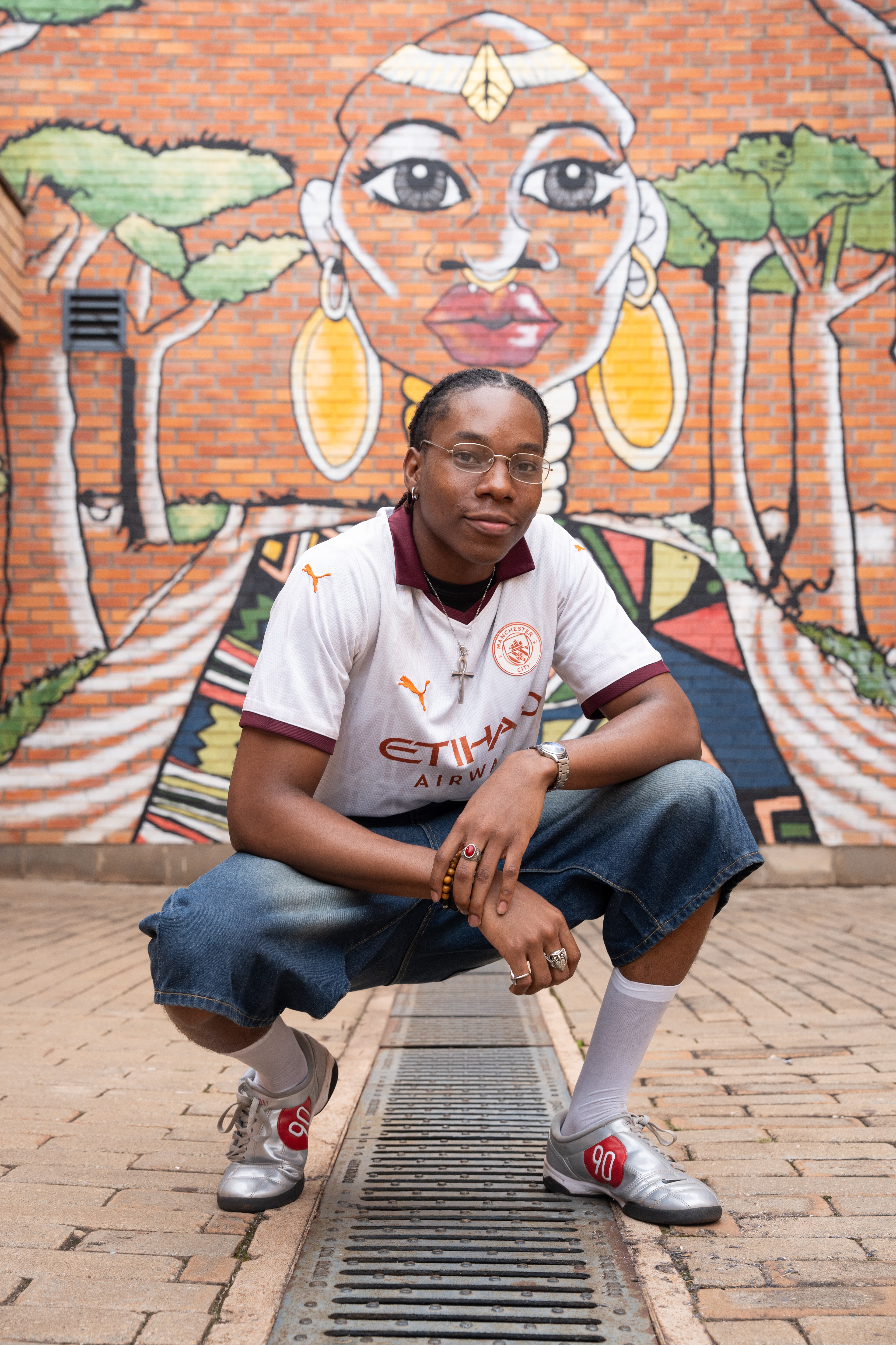 Winston Ngi, 20, is a student at the African Leadership University. ALU students pursue projects to solve problems in their home countries or other countries where they can make an impact. Ngi is studying software engineering, and is building WiyoRent to connect students with houses and fill the student-housing need in Rwanda.   Ngi poses in front of a mural on ALU’s campus that is a nod to African tradition and a look toward the future of technology in Africa.   (Photo/Evan Frilingos 2026)