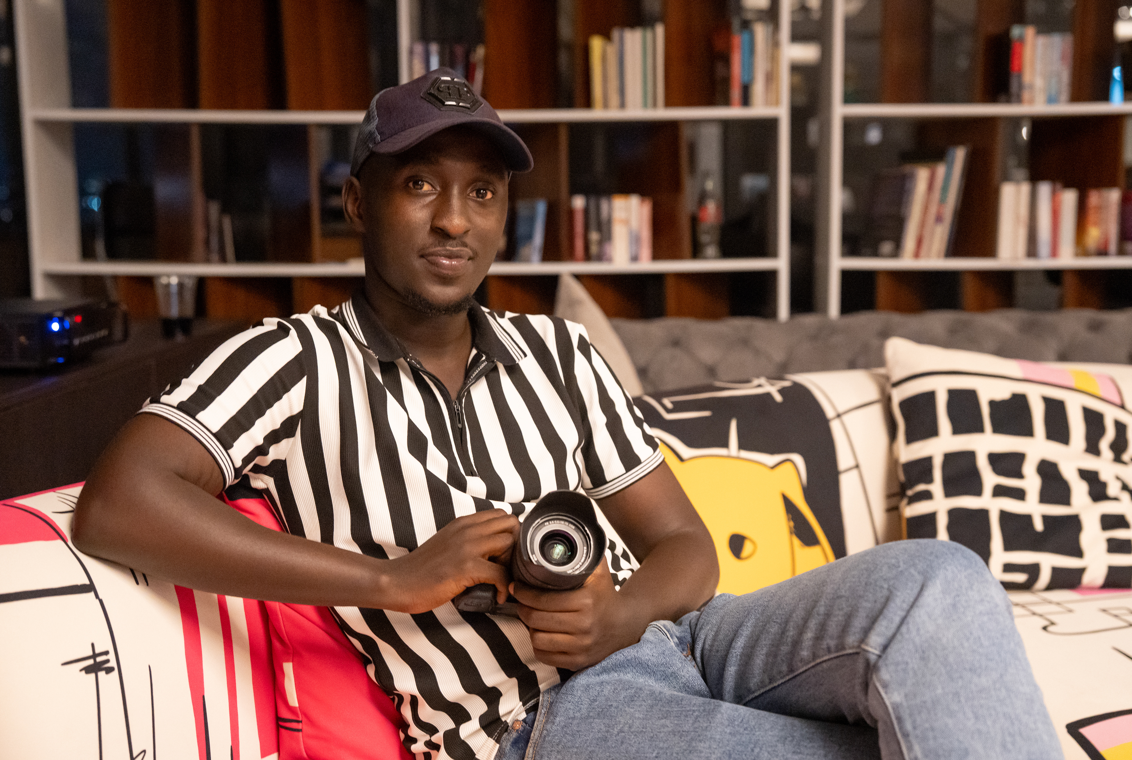 Joshua poses for a photo at The Views in Nyarutarama during a screening of renowned Rwandan filmmaker Eric Kabera’s film “Africa United.”   Joshua is one of many aspiring young filmmakers, videographers and photographers who are students of Eric Kabera and his Kwetu Film Institute.   The Kwetu Film Institute invests in and educates its students to make Rwanda a leading regional nation for digital media and produce professionals ready for the highest level of the industry, according to its website.   CNBC Africa said Rwanda’s film industry accounted for 5% of the country’s GDP in 2022, and UNESCO said in 2025 that the young creative arts generation is reclaiming Rwanda’s future.   (Photo/Evan Frilingos 2026)