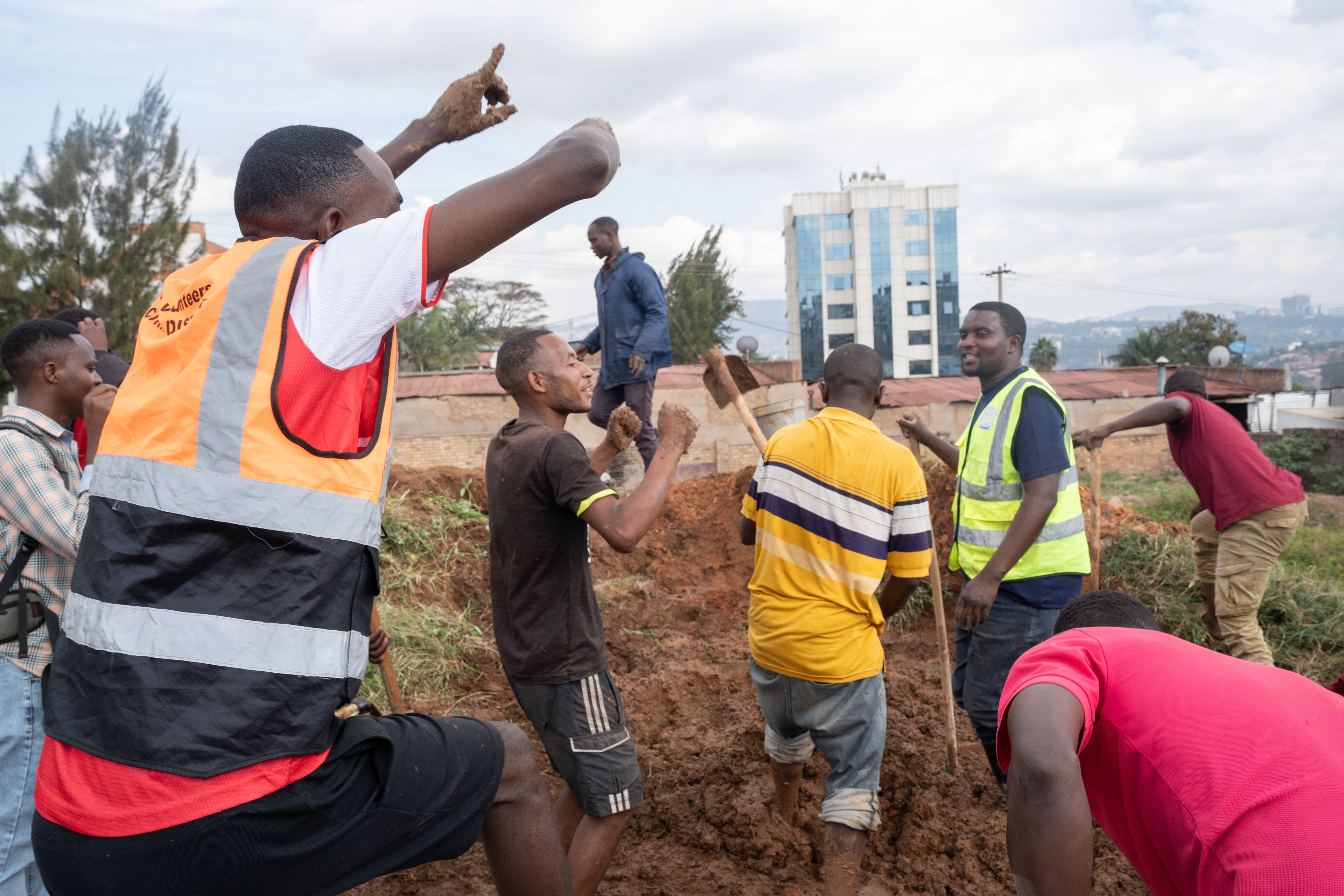 Participators in Umuganda, the national monthly day of service, dance and sing while making mud on Saturday, May 30, 2026 in Kigali, Rwanda. The mud would be turned into bricks to construct a home for orphans in the community.  Umuganda, which means “coming together in common purpose” in Kinyarwanda, is a mandatory day of service on the last Saturday of each month. Public projects commence including trash cleanup, home building, tree planting and more.   The practice was re-established after the genocide as a way to bring communities together over the shared purpose of reconstruction, reconciliation and national pride. (Photo/Evan Frilingos 2026)