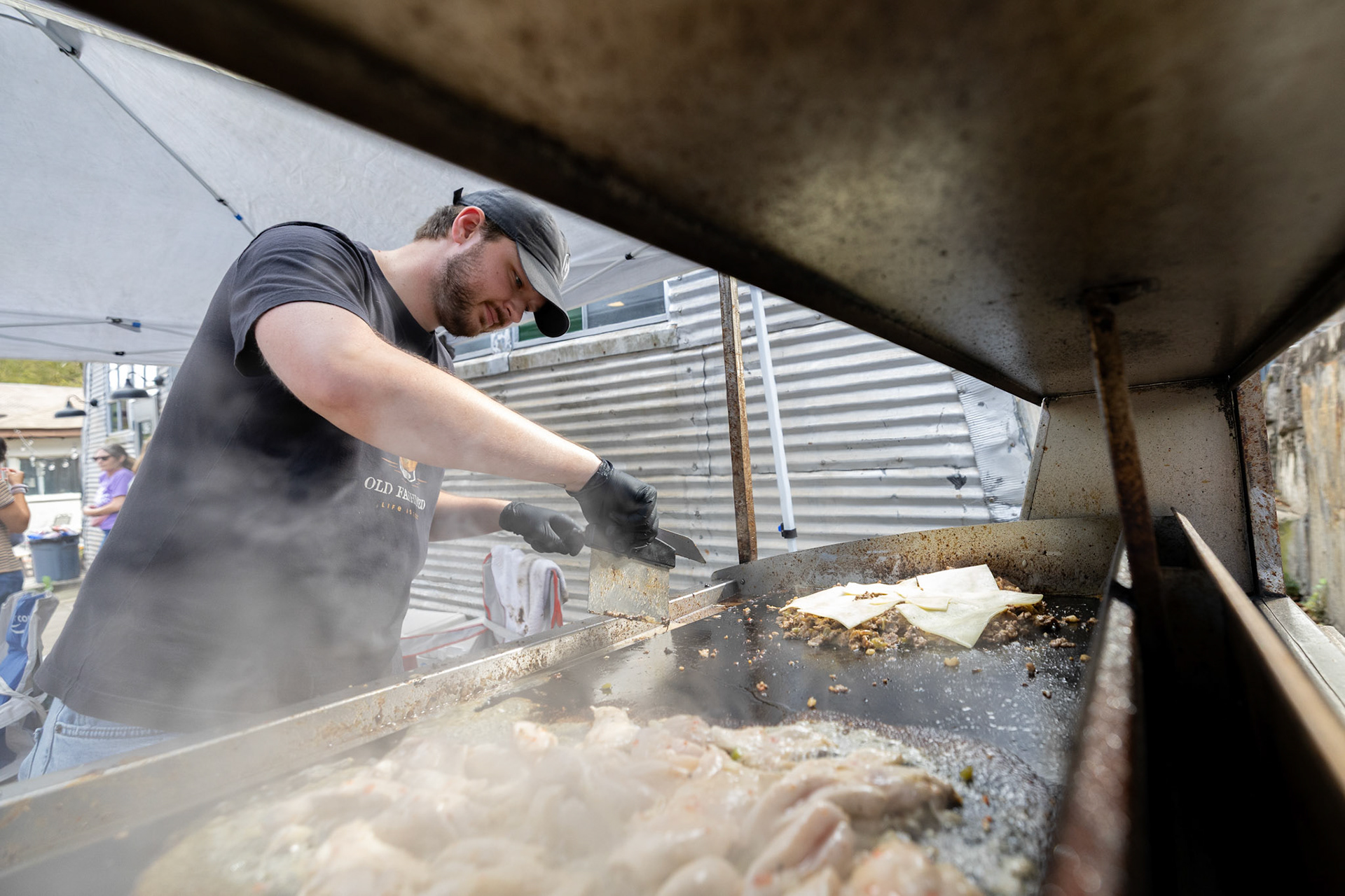 Luke Garrett grills meat for Darby’s Cheesesteak during Porchfest in Athens, Georgia on Sunday, Oct. 19, 2025. Garrett graduated with a public relations degree from the University of Georgia in August, and also works the grill at Five Guys. (Photo/Evan Frilingos)