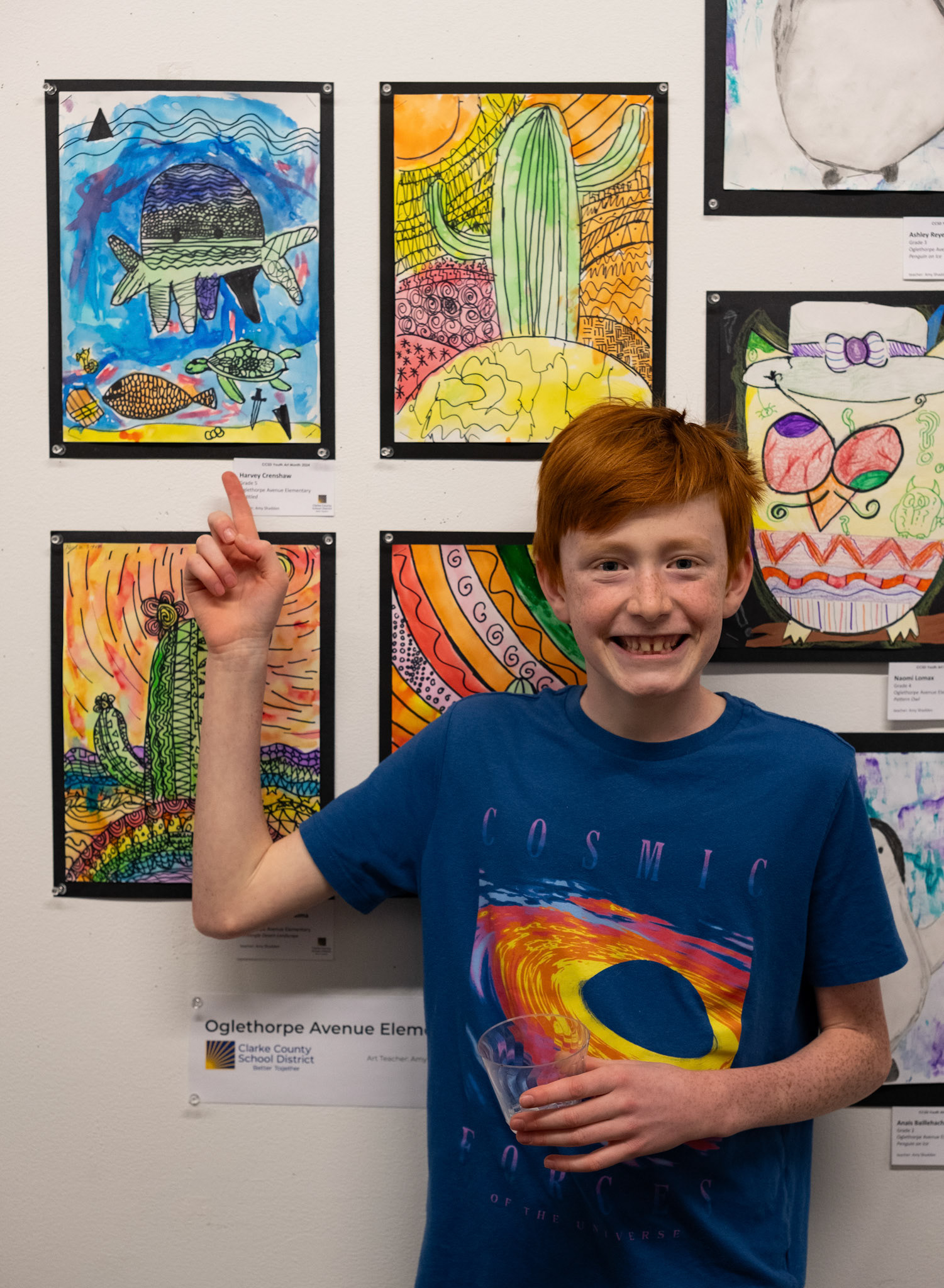 Harvey Crinshaw points to his piece "Untitled" at the CCSD Youth Art Exhibition at the Lamar Dodd School of Art in Athens, Georgia on Sunday, March 24, 2024. Crinshaw wanted to use cool colors in his piece, creating a contrast with the other warm color pieces. (Photo/Evan Frilingos; @frilingos.photos)