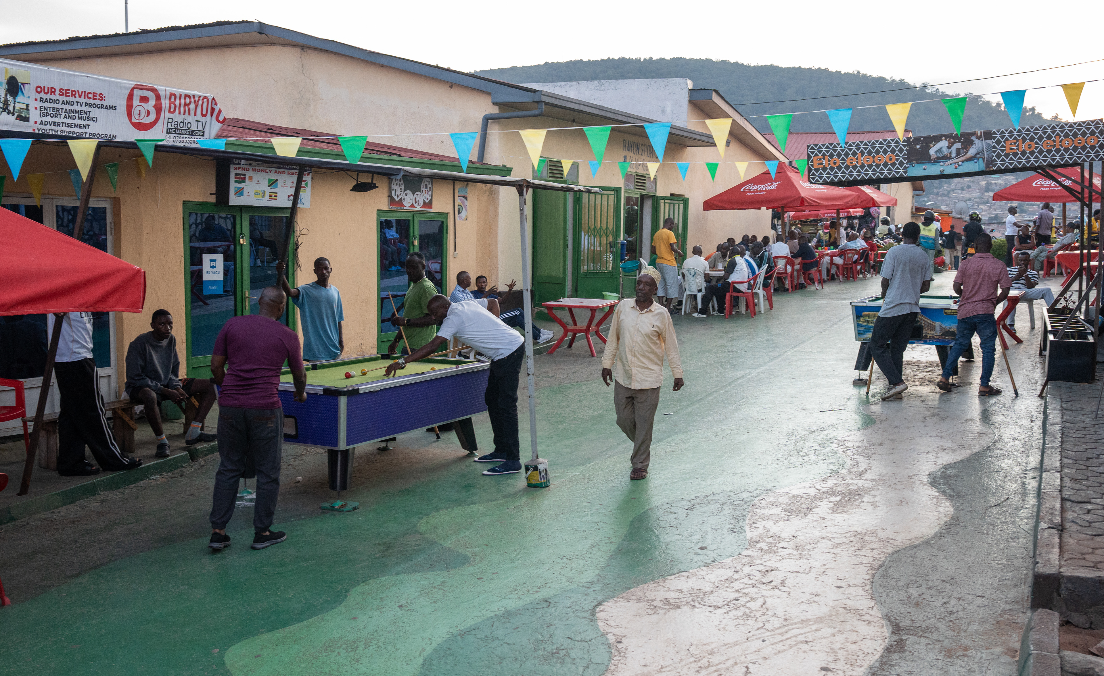 Men play pool in the evening on Sunday, May 17, 2026 in the Nyamirambo neighborhood in Kigali, Rwanda.   Games and sports have been a fixture of Rwandan society for centuries. One of the most famous was Gusimbuka Urukiramende, which is similar to a high jump and dates to pre-colonization, tasked men with jumping over bars that were raised to heights above two meters, according to The Conversation.  Today, pool is growing in popularity and pool tables often fill restaurant and cafe parlors. The walkable Nyamirambo neighborhood is filled with pool tables on sidewalks and walkways. (Photo/Evan Frilingos 2026)