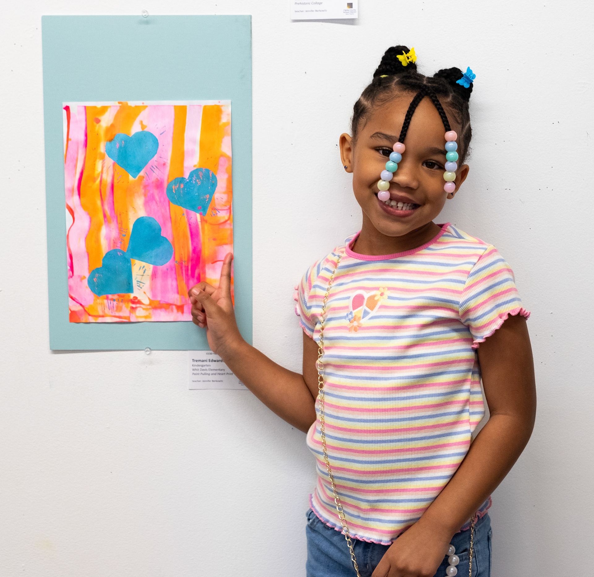 Tremani Edwards poses next to her piece "Paint Pulling and Heart Print" at the CCSD Youth Art Exhibition at the Lamar Dodd School of Art in Athens, Georgia on Sunday, March 24, 2024. Her favorite part of the process was making the hearts. (Photo/Evan Frilingos; @frilingos.photos)