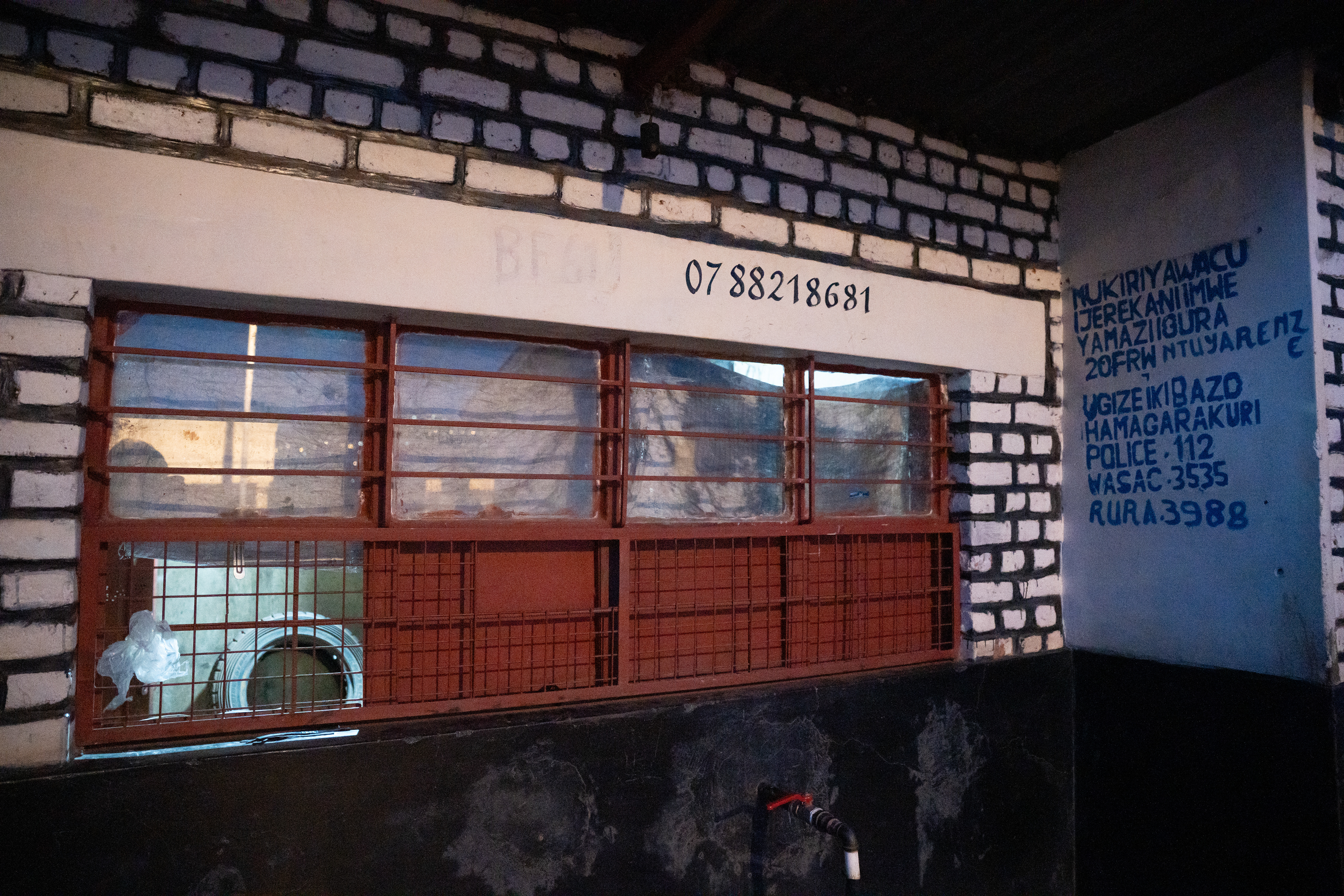 A tap water building serves people looking to purchase clean water for a minimal price on Sunday, May 17, 2026 in Kigali, Rwanda.   These buildings are part of a government effort to increase public access to cheap, clean water. They contain spring water from nearby Mount Kigali and writing on the wall instructs customers to call the police if the prices are raised by local managers.  During the genocide, water infrastructure was damaged and destroyed across the country. Water has since become a priority in Rwanda, evidenced by the creation of the Rwanda Water Resource Board and commitment to aligning itself with the United Nations’ Sustainable Development Goal 6 of universal access to safe and affordable drinking water by 2030.  Access to improved drinking water sources rose to from about 64% in 2000 to 90% by 2024, according to Rwanda’s government and UNICEF. Those sources have also gotten significantly closer to homes and more widespread in rural areas. (Photo/Evan Frilingos 2026)