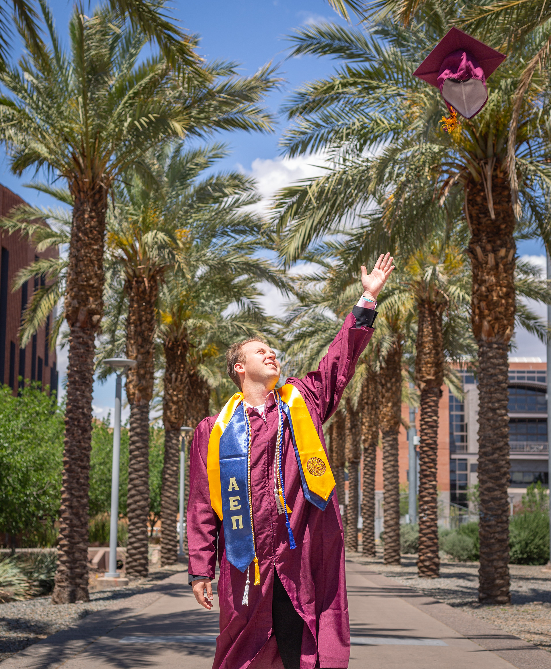 Tyler Baum, Arizona State University graduate, throws his cap in the air on the ASU palm walk in Tempe, Arizona.