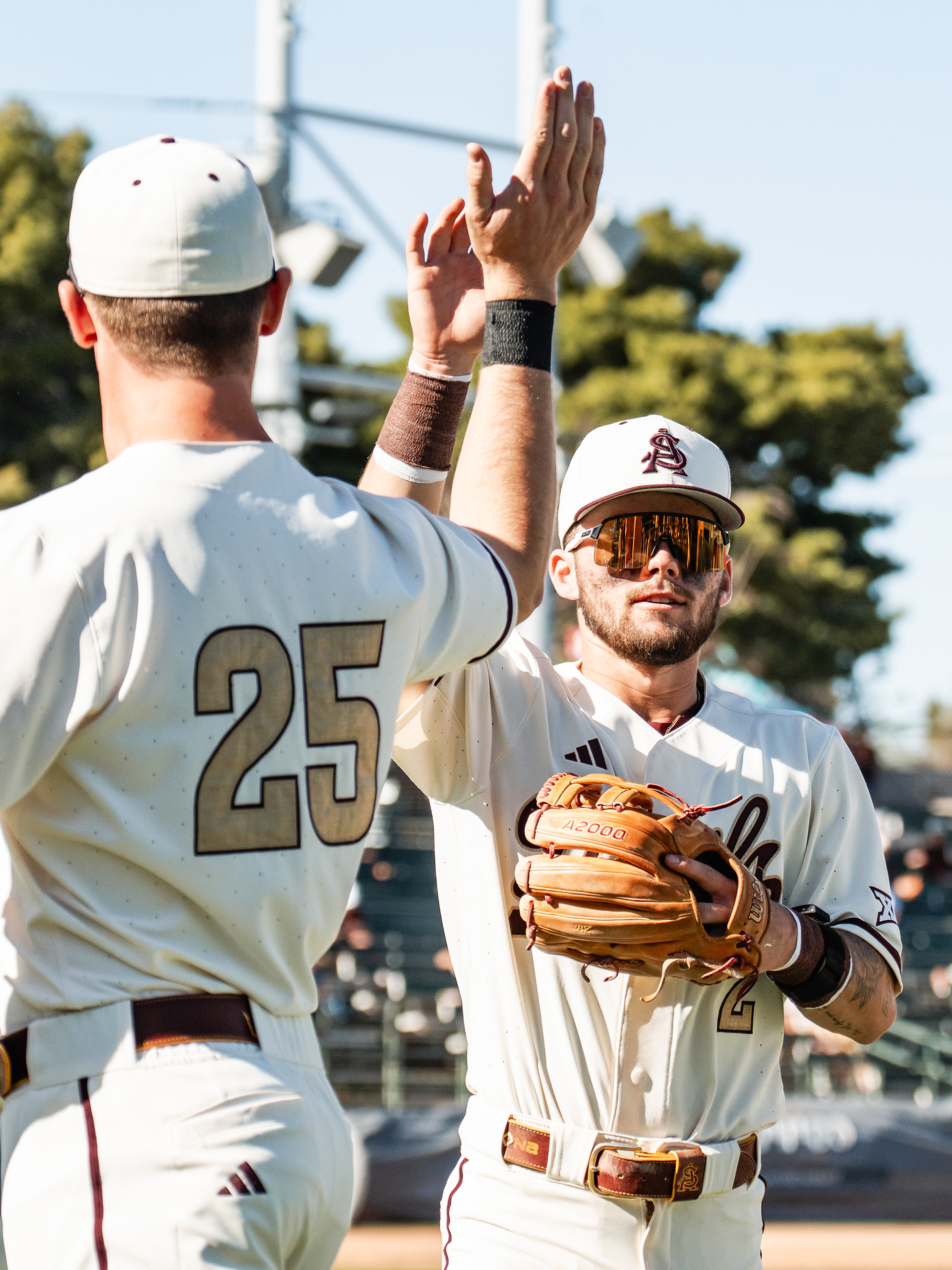 Dominic Smaldino and Beckett Zavorek, Arizona State University infielders, high five while coming back into the dugout after the top half of an inning during a home game against St. John’s University at Phoenix Municipal Stadium on Sunday, February 22, 2026 in Phoenix, Arizona. 