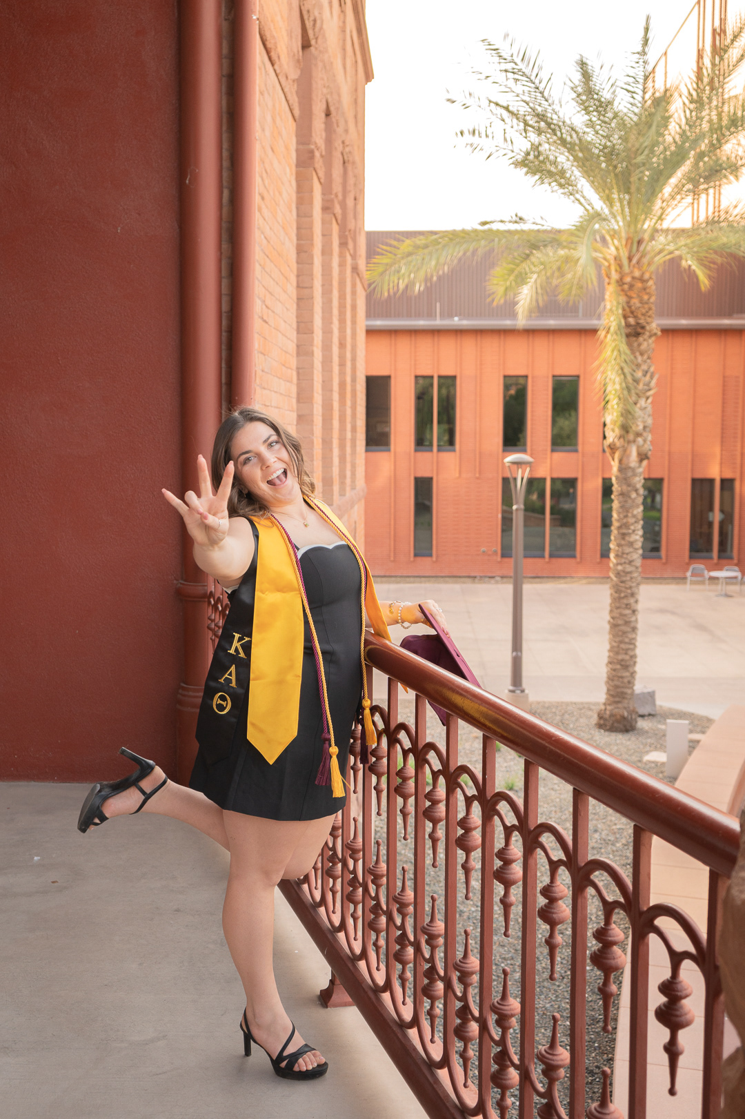 Kaitlyn Wolfe, Arizona State University graduate, gives the “forks up” sign while outside Old Main in Tempe, Arizona.