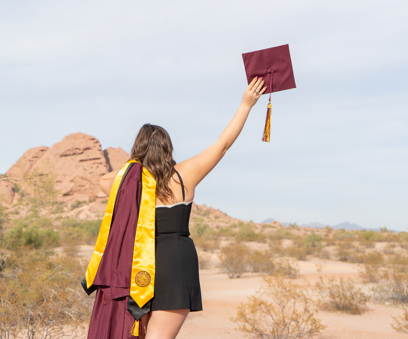 Kaitlyn Wolfe, Arizona State University graduate, poses with her cap and gown at Papago Park in Phoenix, Arizona.