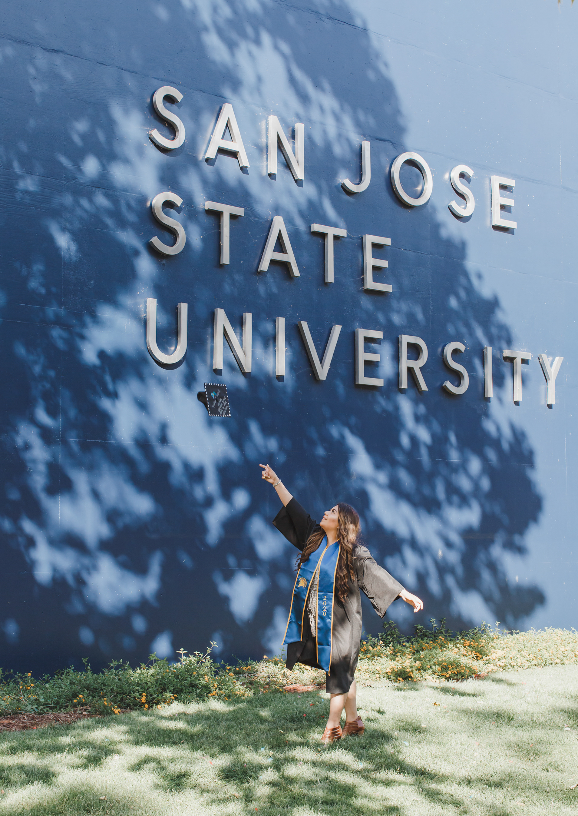 San Jose State University graduate tosses her cap in the air in front of the SJSU sign in San Jose, California.