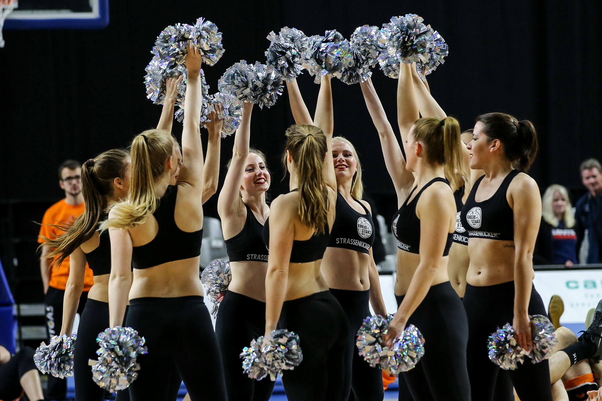 Gruppe Cheerleader aus Köln hält Hände mit Pompoms in die Luft.