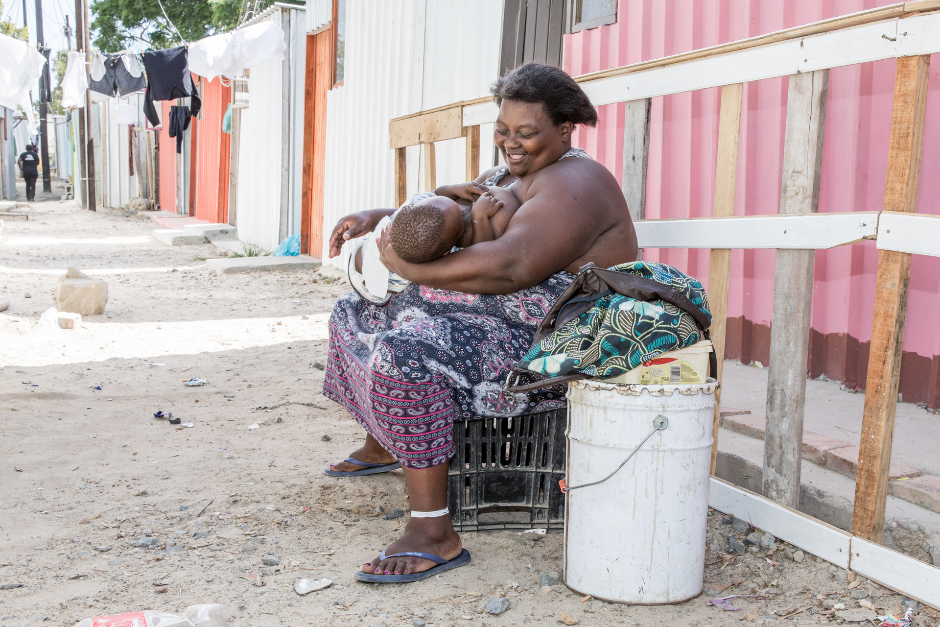 Khowulezile Mcaphukisi breast feeds her baby outside the 3x3 shack she shares with her husband and six children.