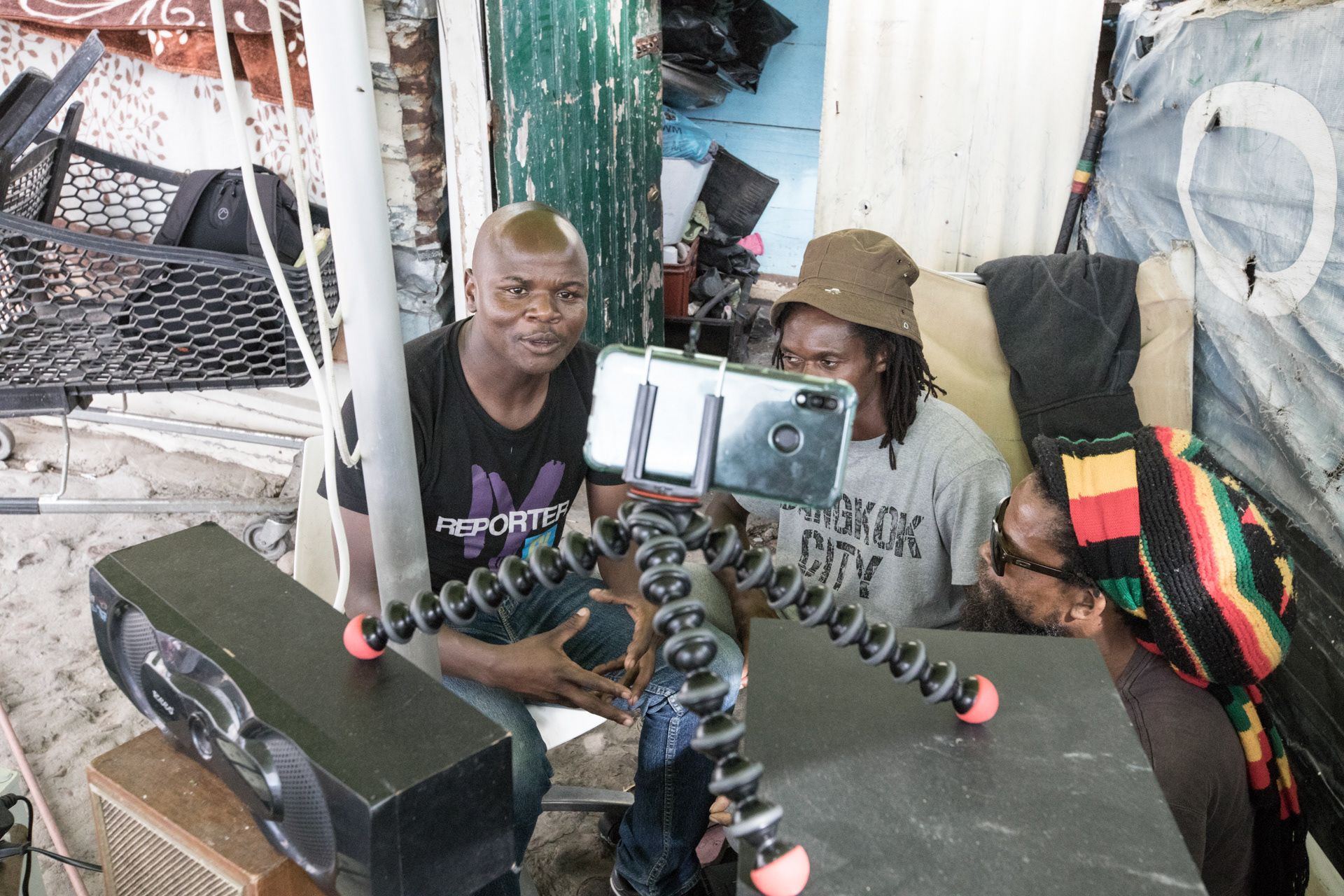 Owen Xubuzane, far left, became intrigued by digital media when he worked as a technician installing internet networks for TooMuchWifi in Imizamo Yethu. He signed up for a workshop at the University of the Western Cape, where he met Cape Digital Foundation CEO Emma Kaye, who appointed him “citizen journalist” for IY TV, an Imizamo Yethu community broadcaster. Here Xubuzane records a segment about faith with a local Rasta.