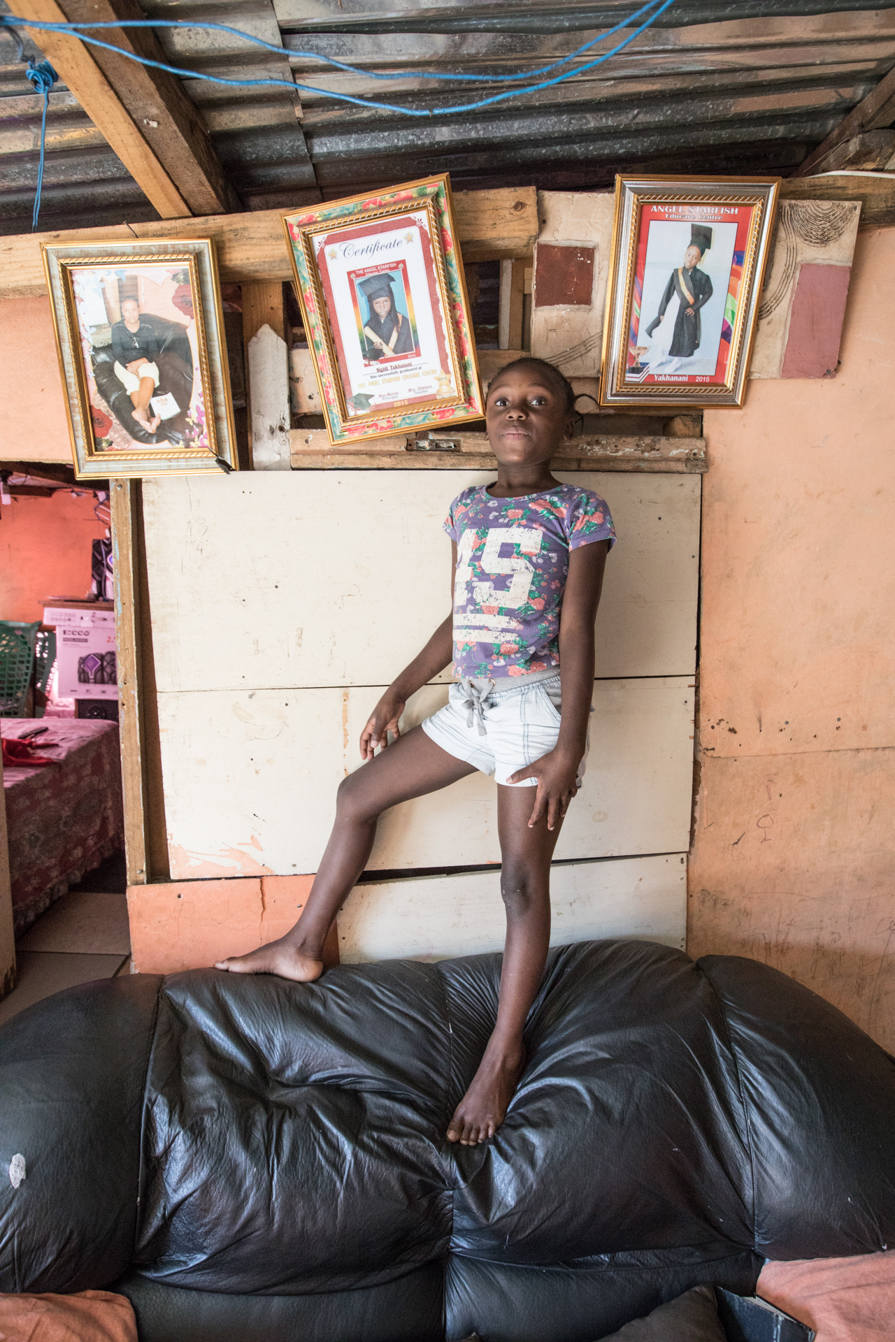Sigidi Yakhanani stands proudly between her school certificates in her family’s home on the upper slopes of IY.
