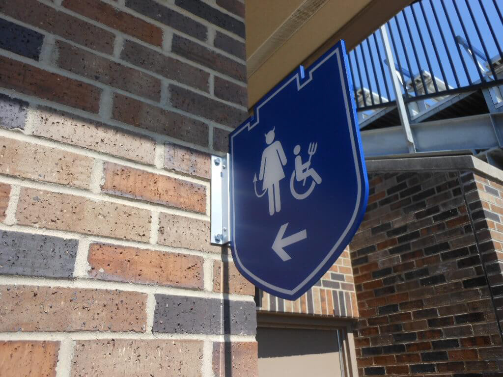 Women's restroom directional "flag" (a.k.a. bracket sign) • milled aluminum with applied vinyl graphics and extruded aluminum mounting bracket • Duke University • Durham, NC