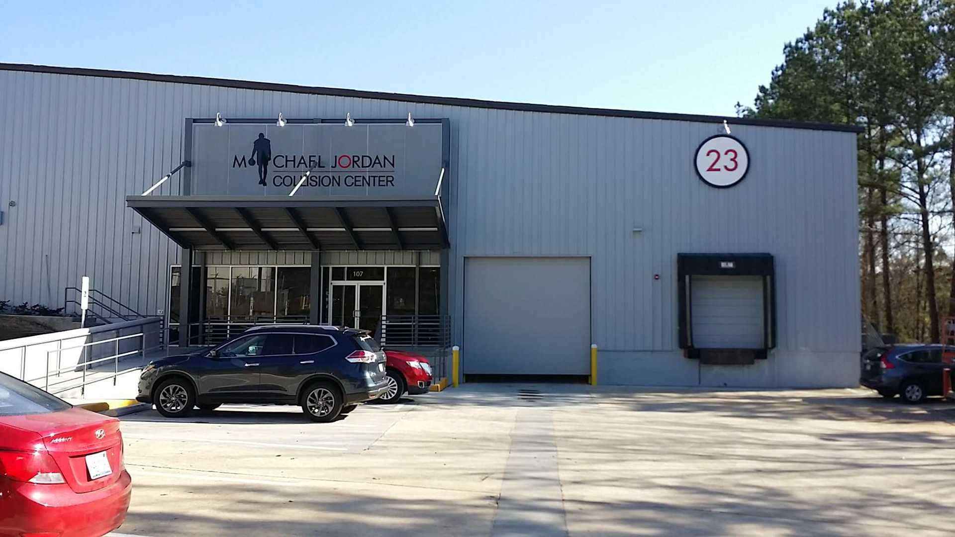 Michael Jordan Collision Center exterior logo (painted acrylic graphics on mesh construction by others) and "23" circle (84" diameter sign panel with applied vinyl graphics) • Durham, NC