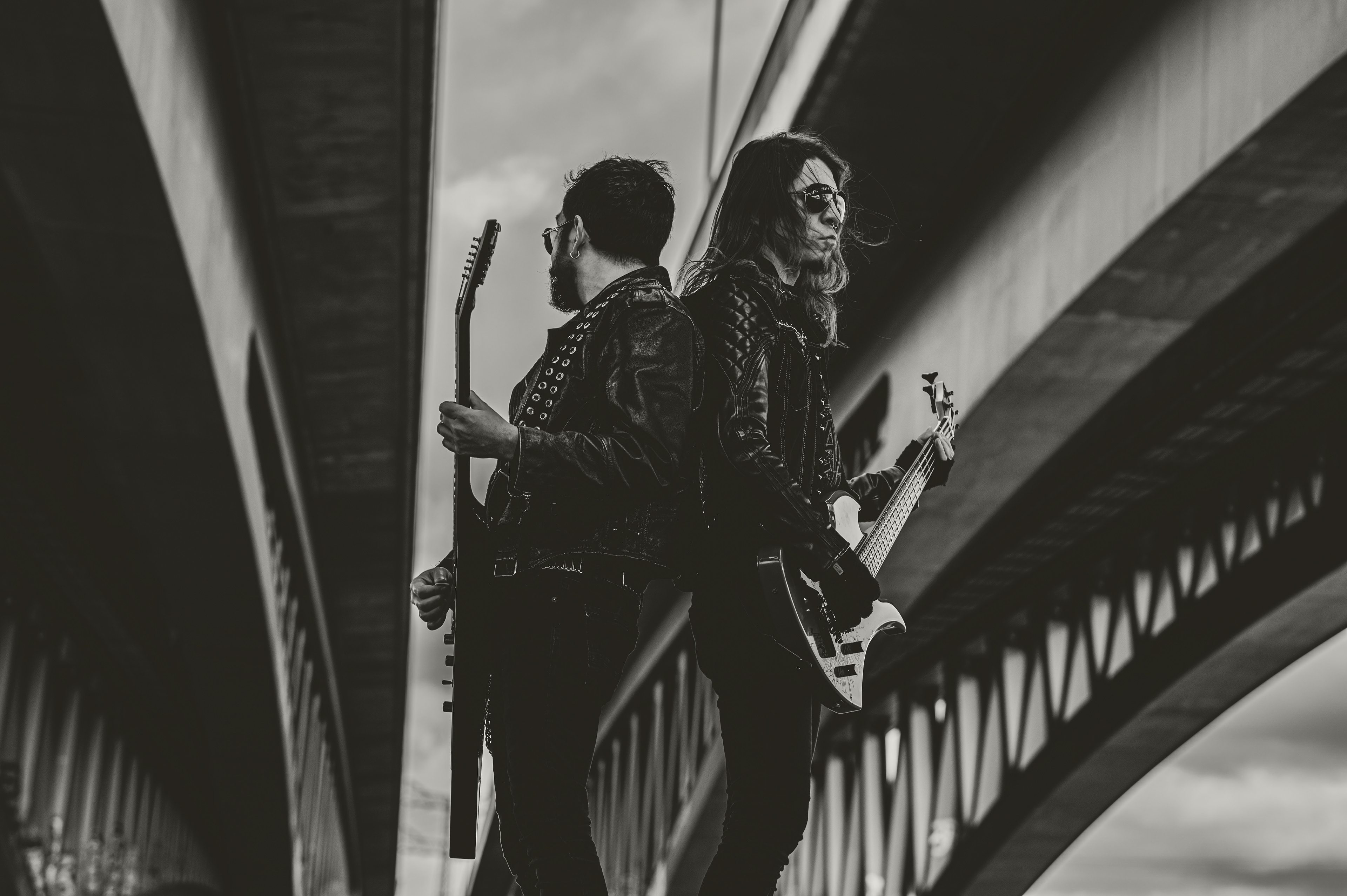 2 musicians with guitars outdoors under the bridge