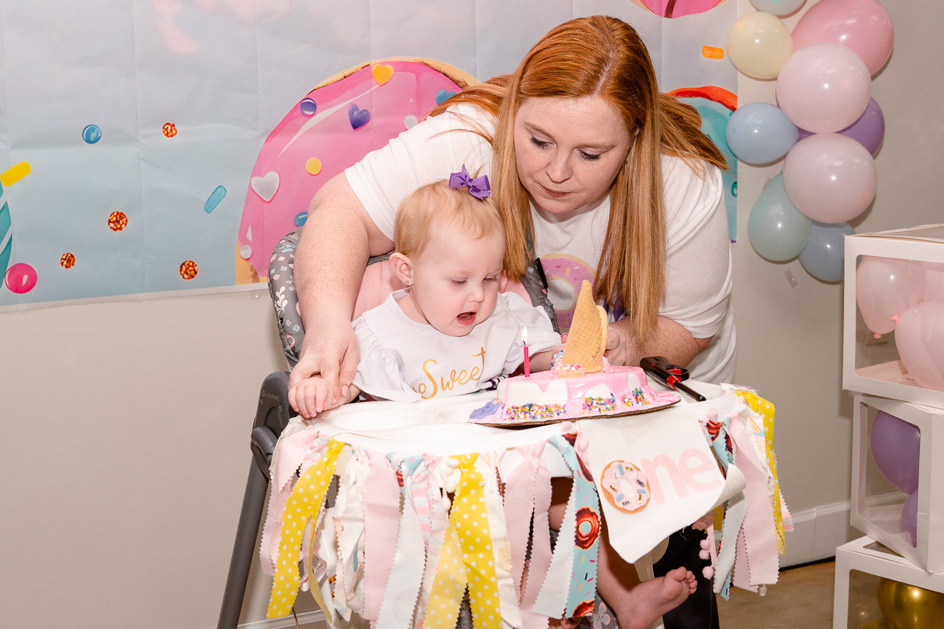 Mom helps daughter blow our her first birthday candle