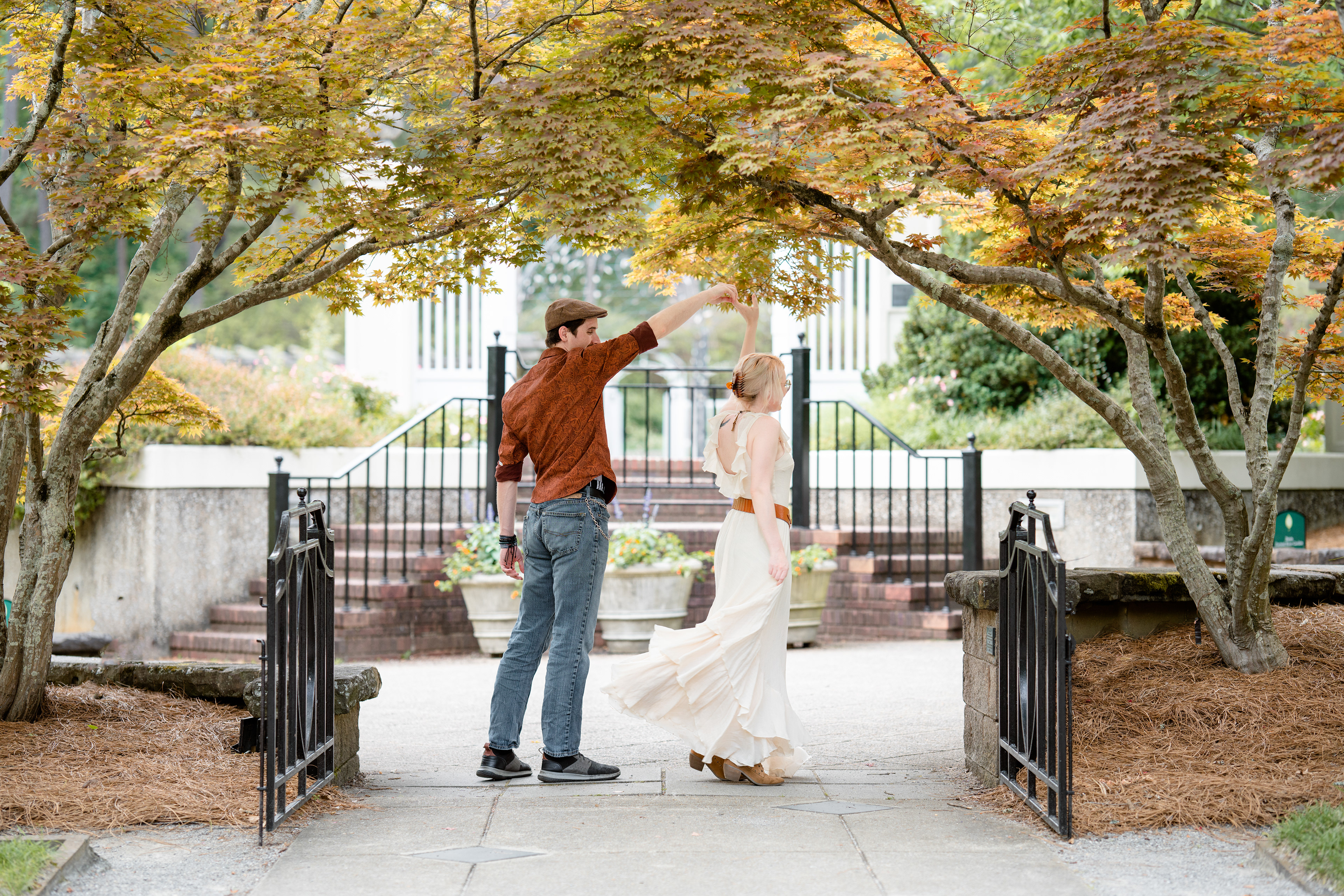 Fiancés dance under colorful trees in an elegant setting 