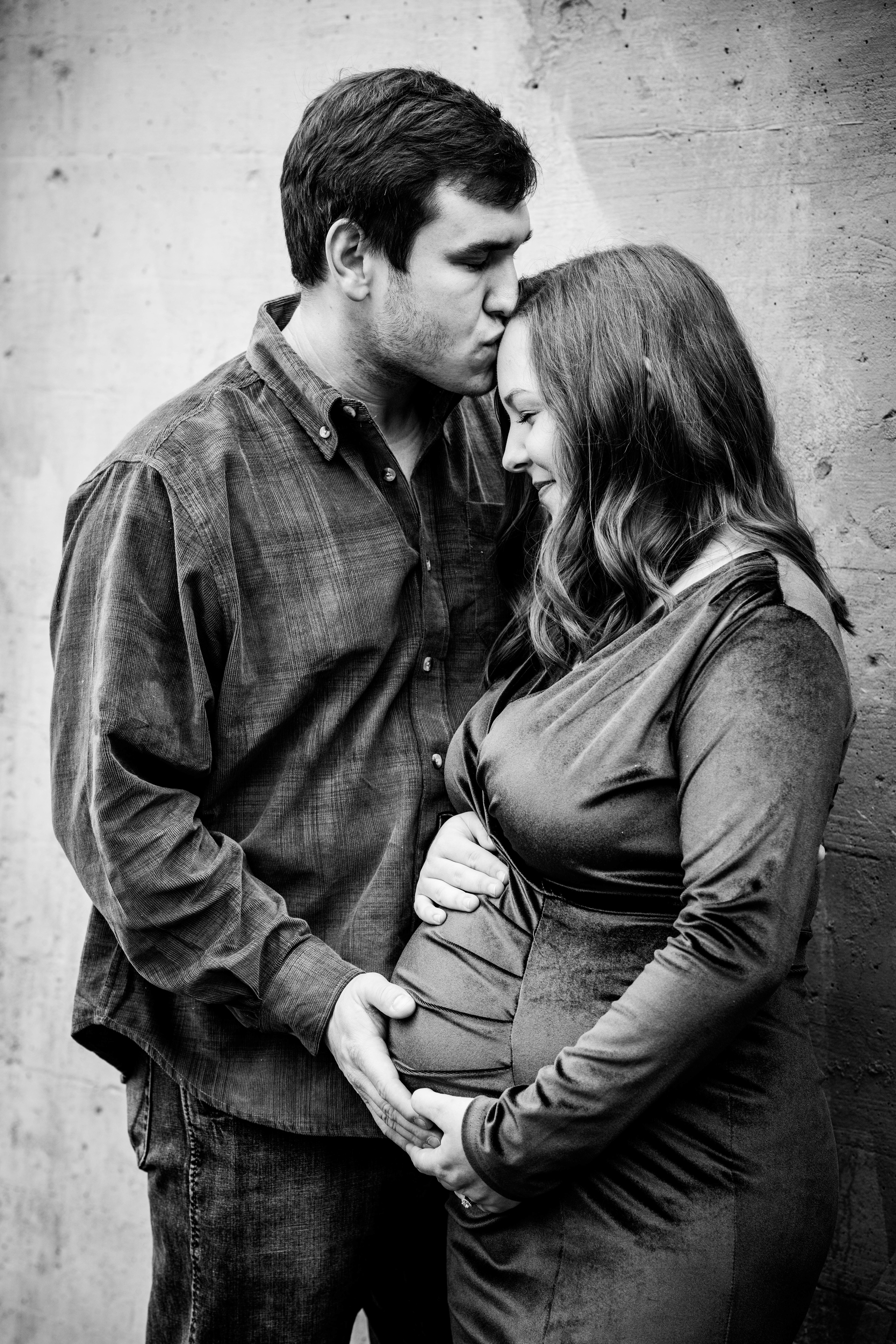 Black and white of husband kissing his pregnant wife