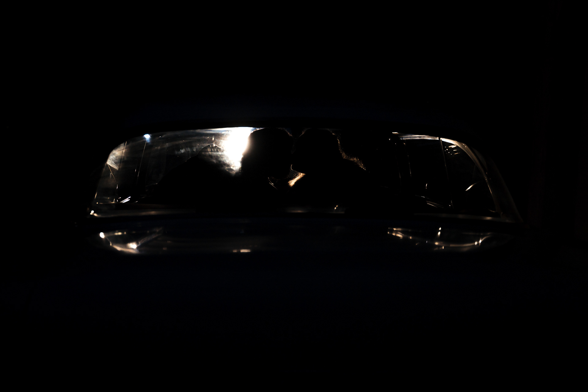 Silhouette of bride and groom sharing a kiss before leaving their wedding