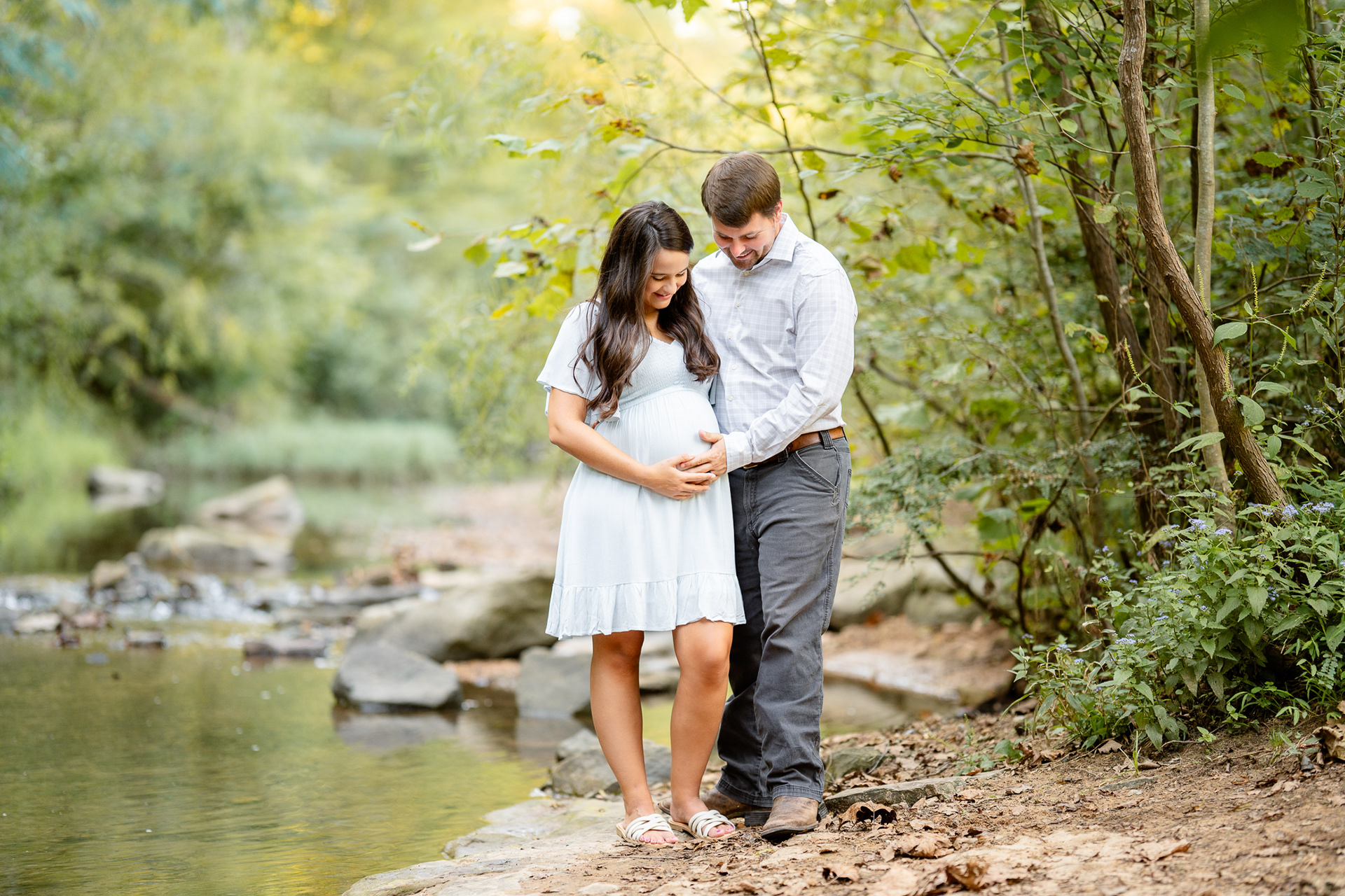 Husband with pregnant wife on the shore of a creek