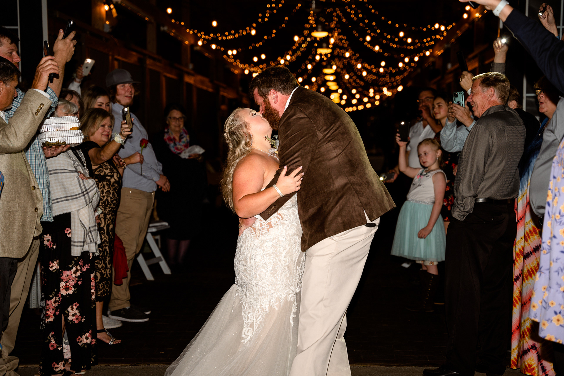 Bride and groom exit the venue among guests' cell phone lights