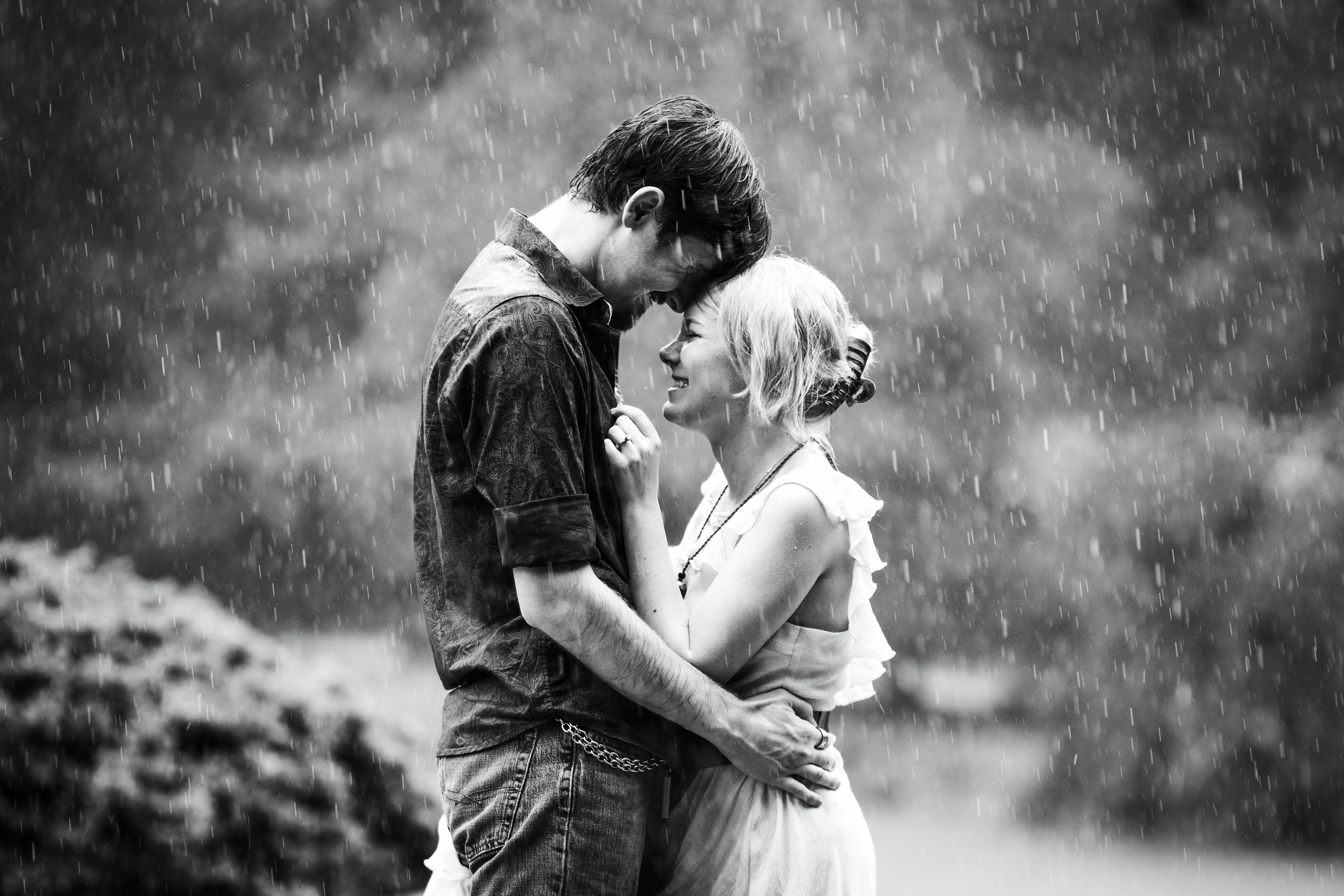 Black and white engagement photo of couple embracing in the rain