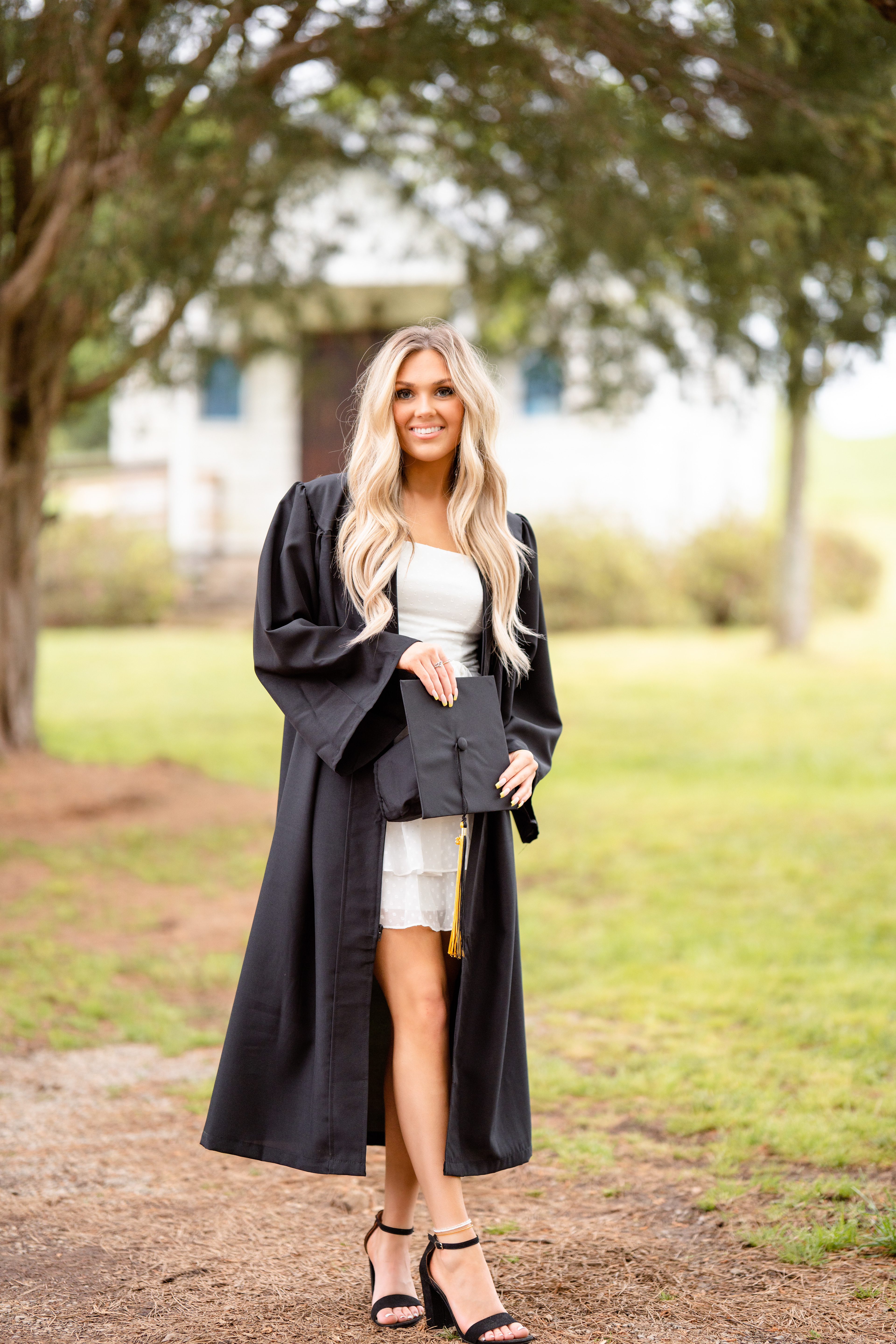 Senior stands in front of an old church in her graduation gown