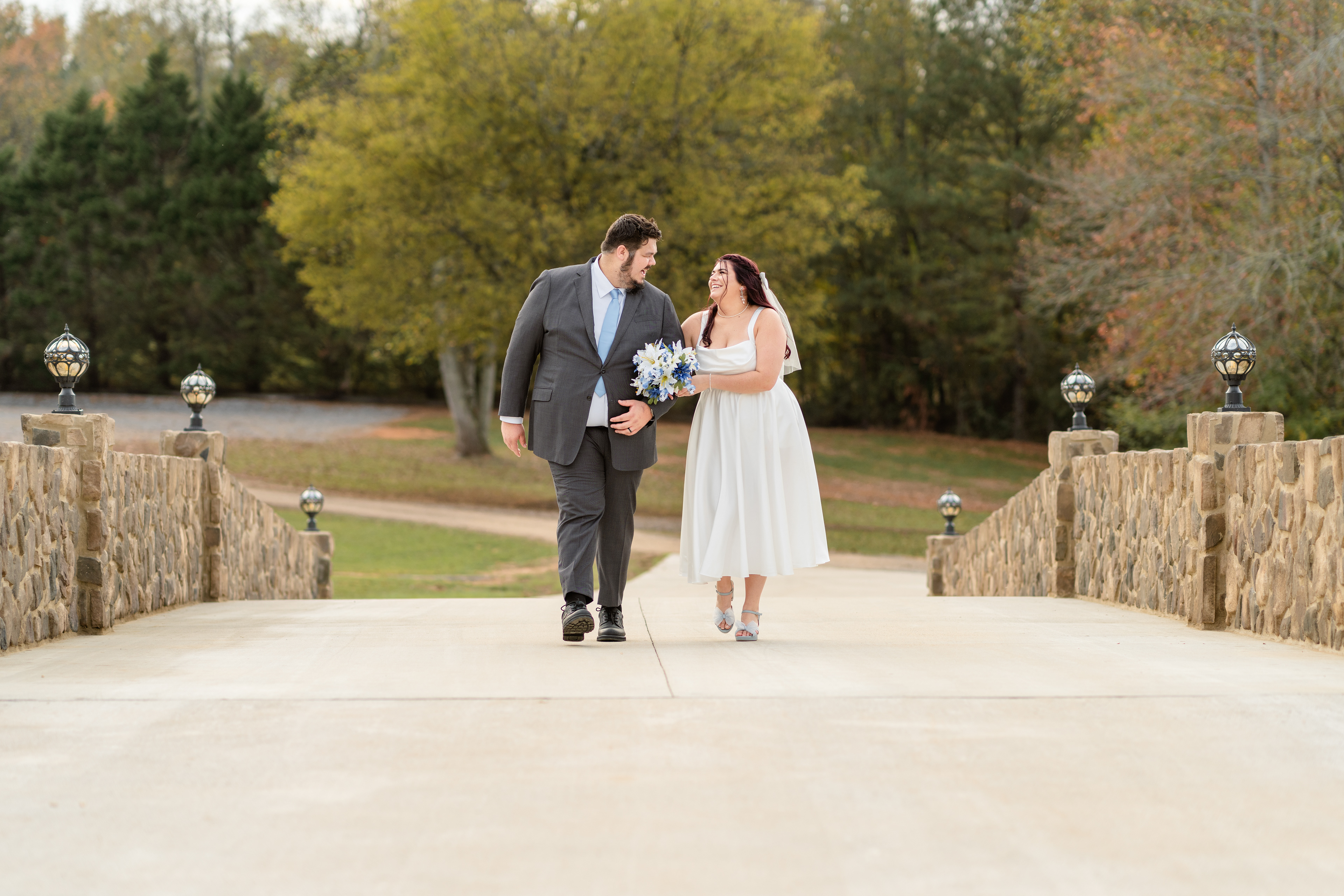Newly weds have a fun walk across pretty bridge