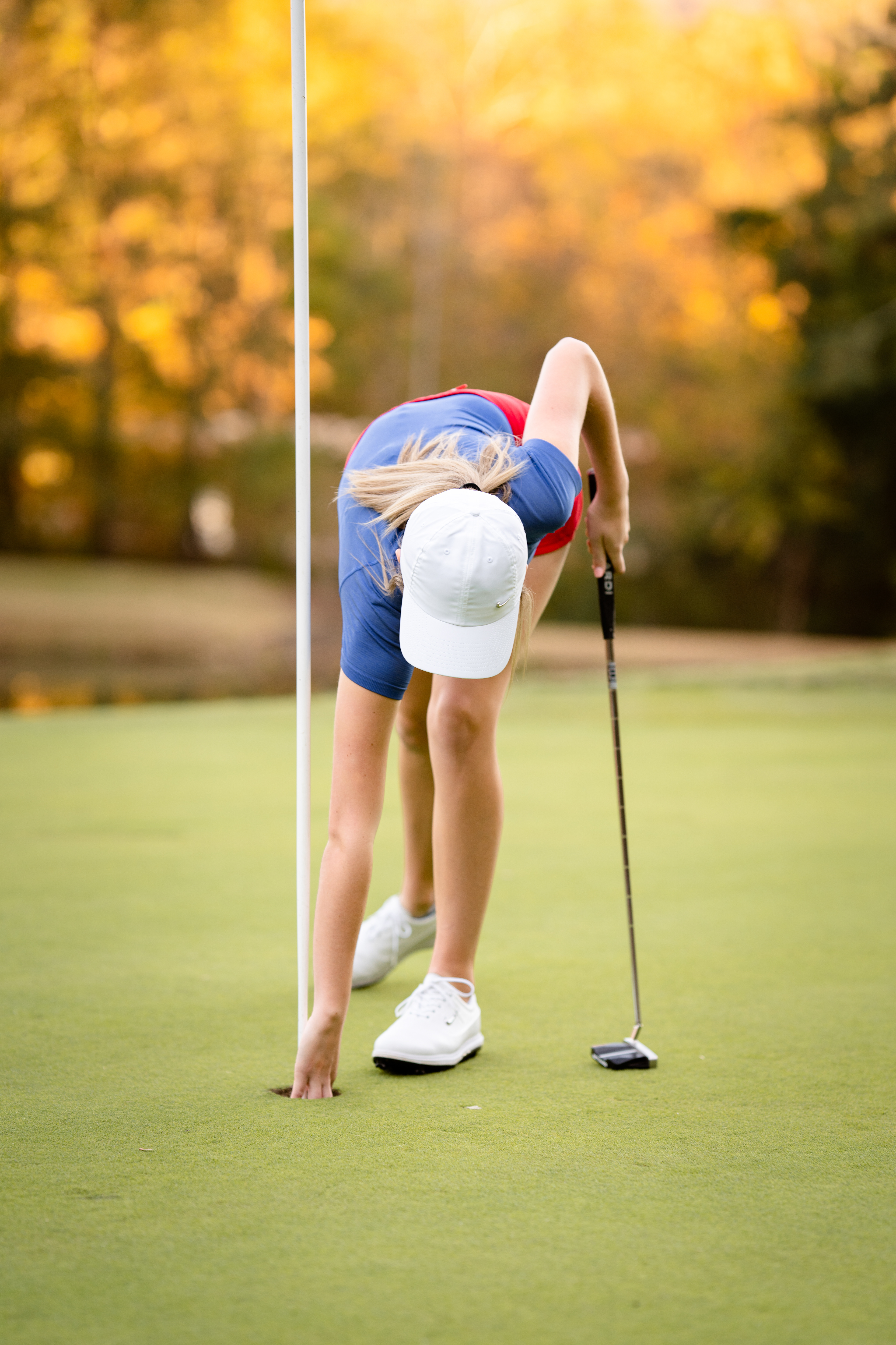 Golfer picks up her ball after sinking a hole