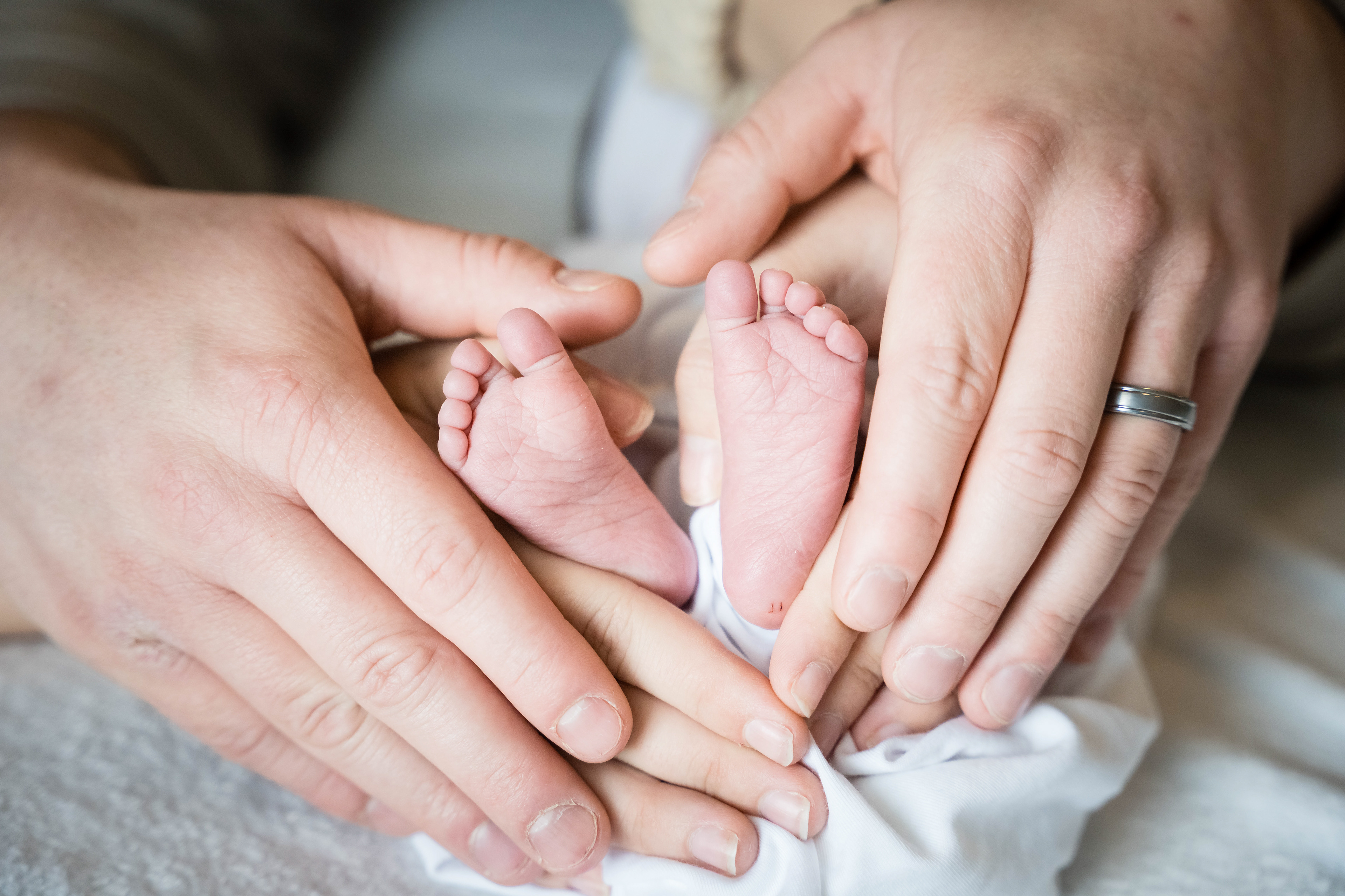Mom and Dad's hands make heart around their newborn daughter's feet