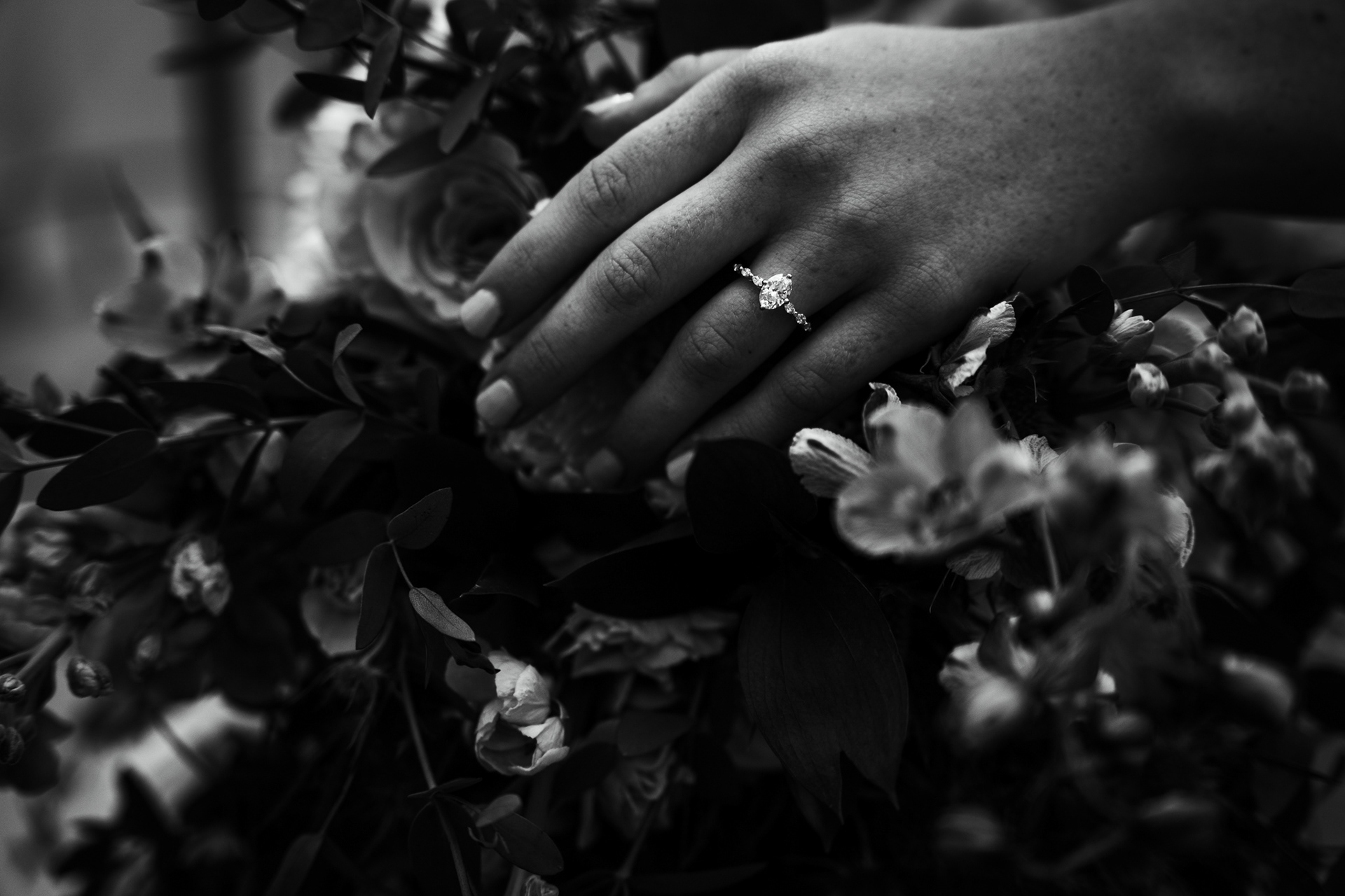 black and white of engagement ring against bouquet