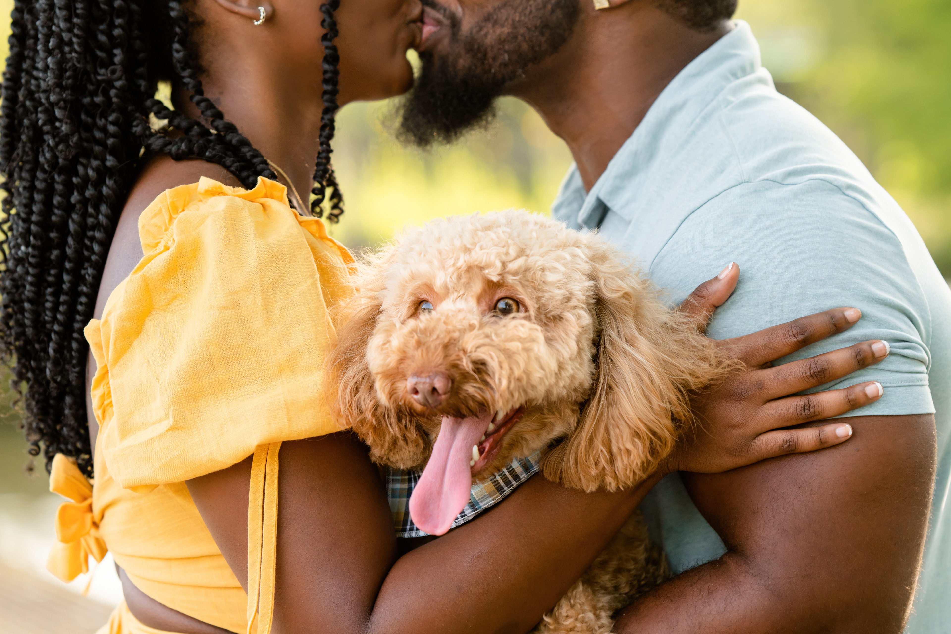 Pet owners kiss while holding their fur baby