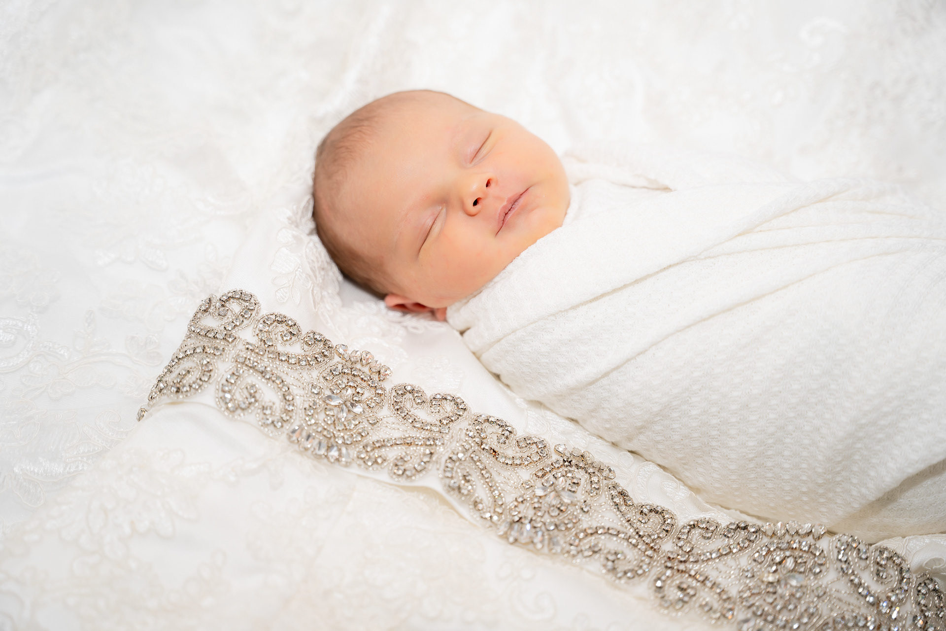 Newborn sleeps on mother's wedding dress