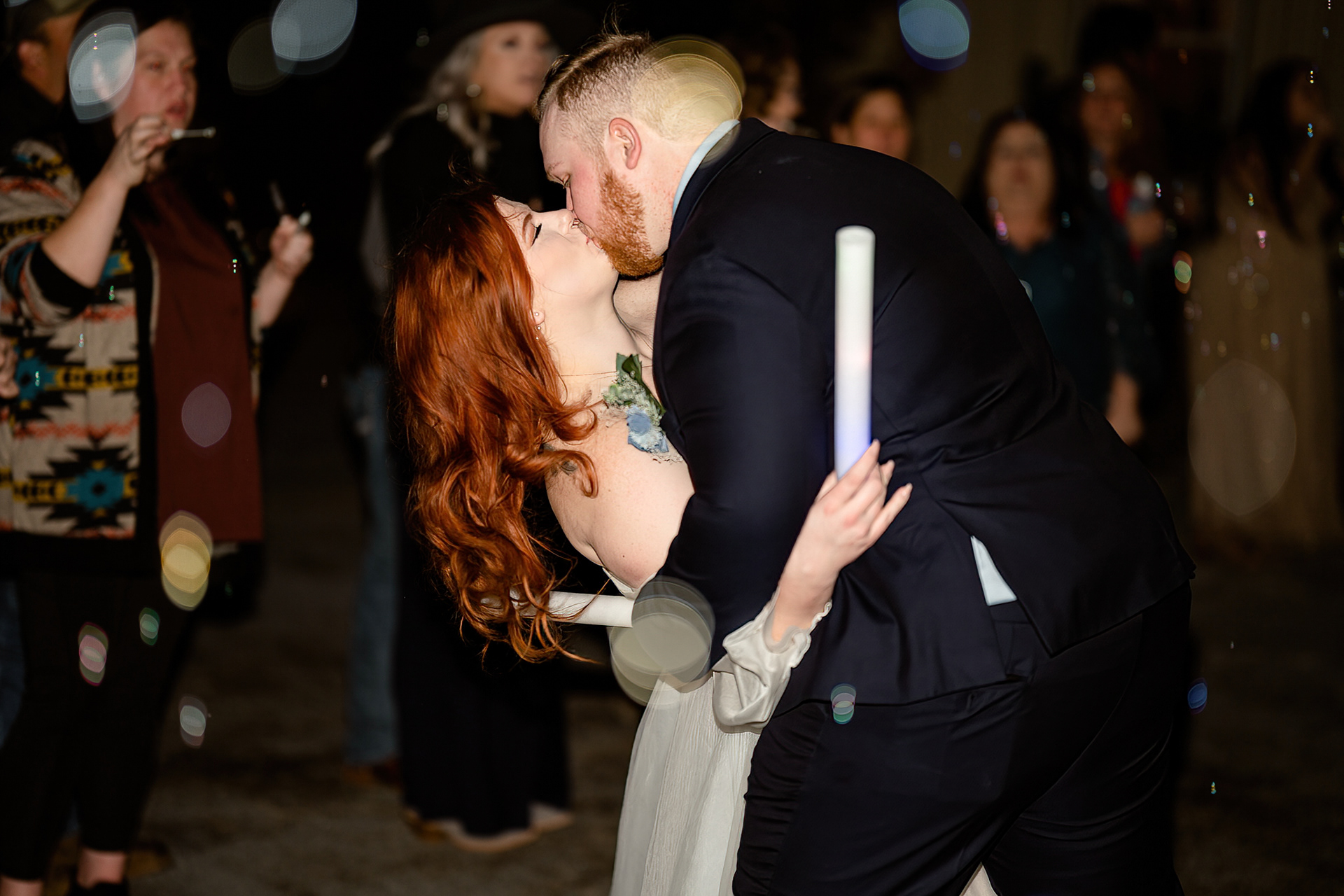 Husband and wife kiss at bubble exit from wedding reception
