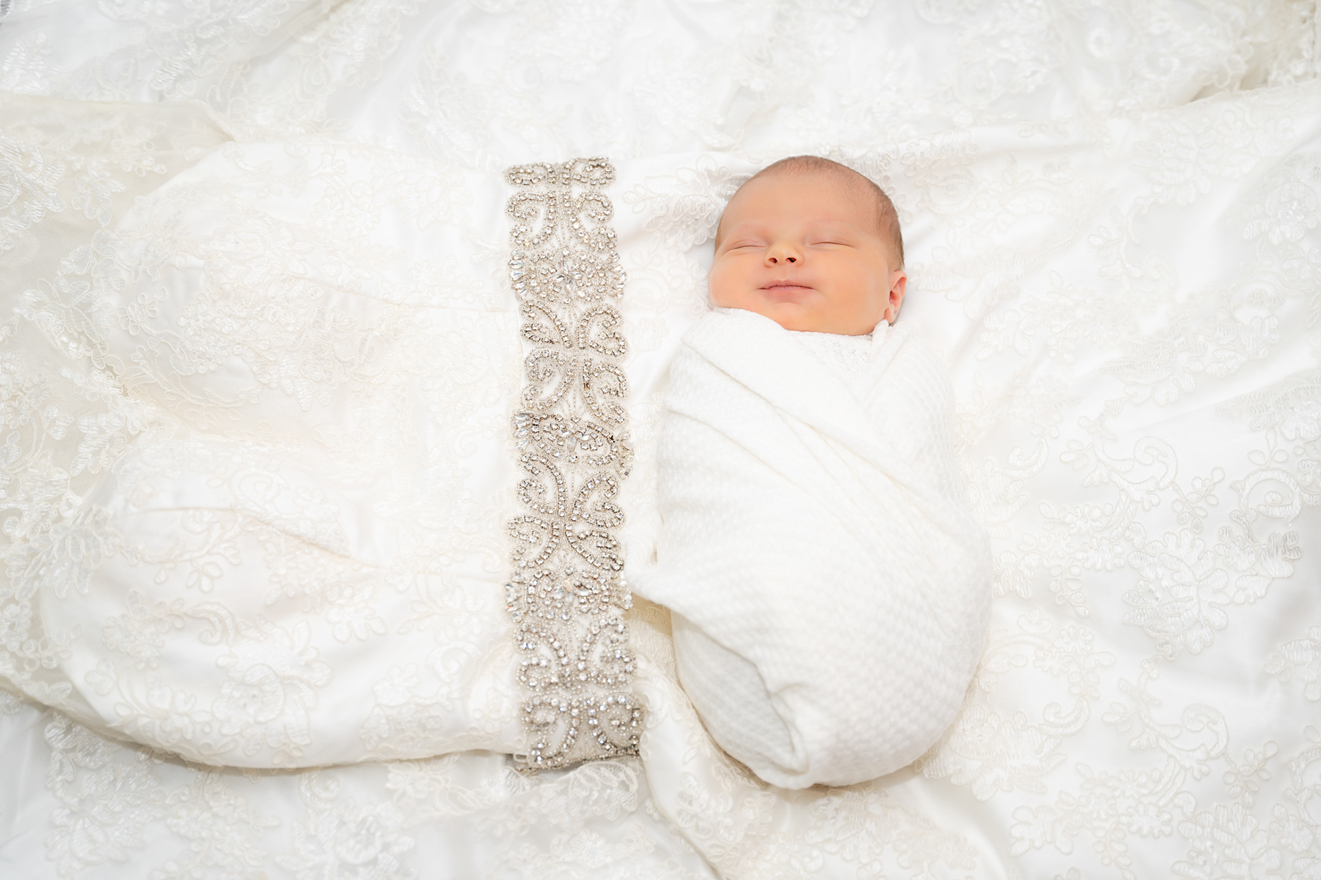 Newborn baby lays on mother's wedding dress