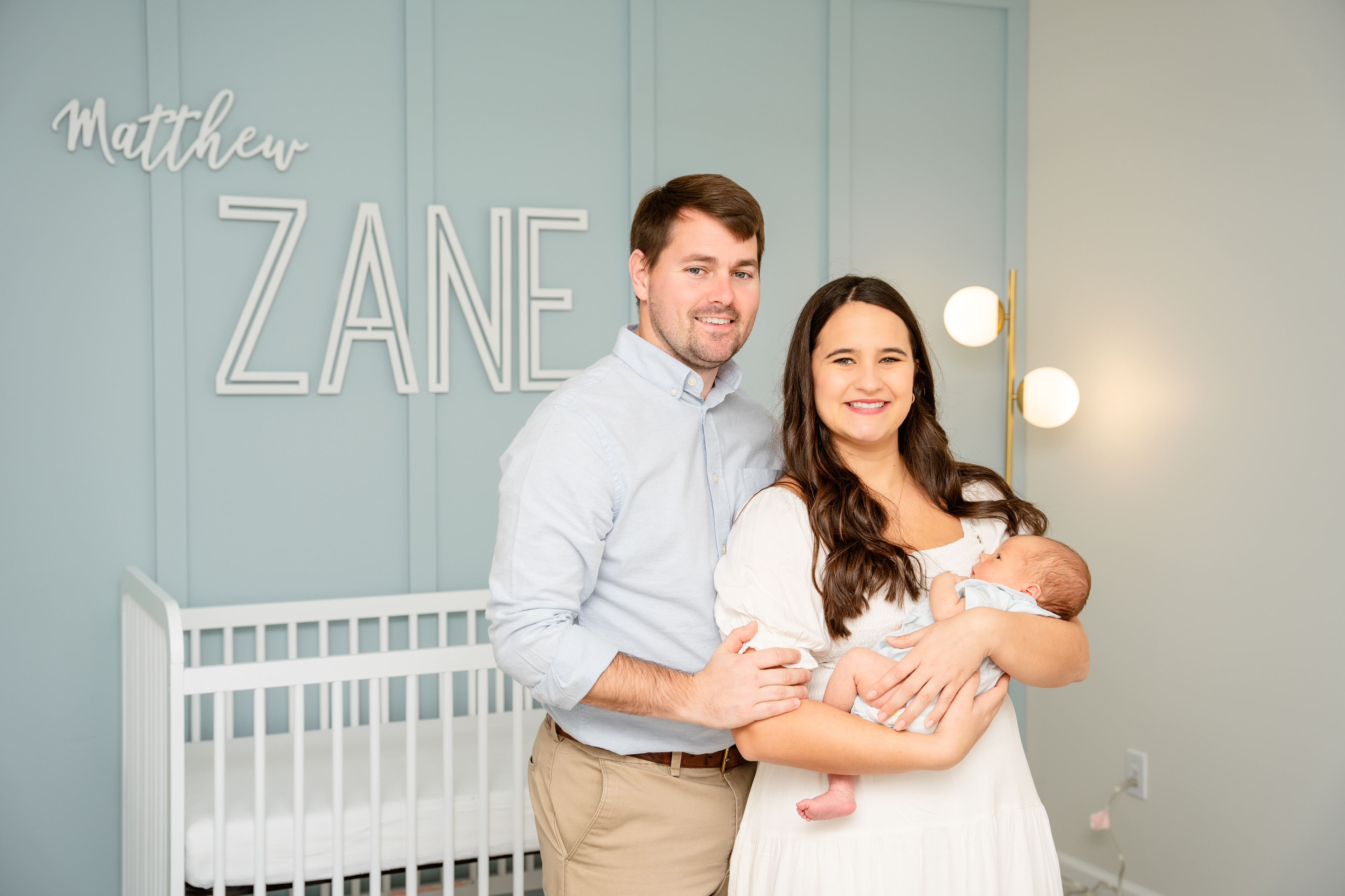 New parents stand in nursery with newborn